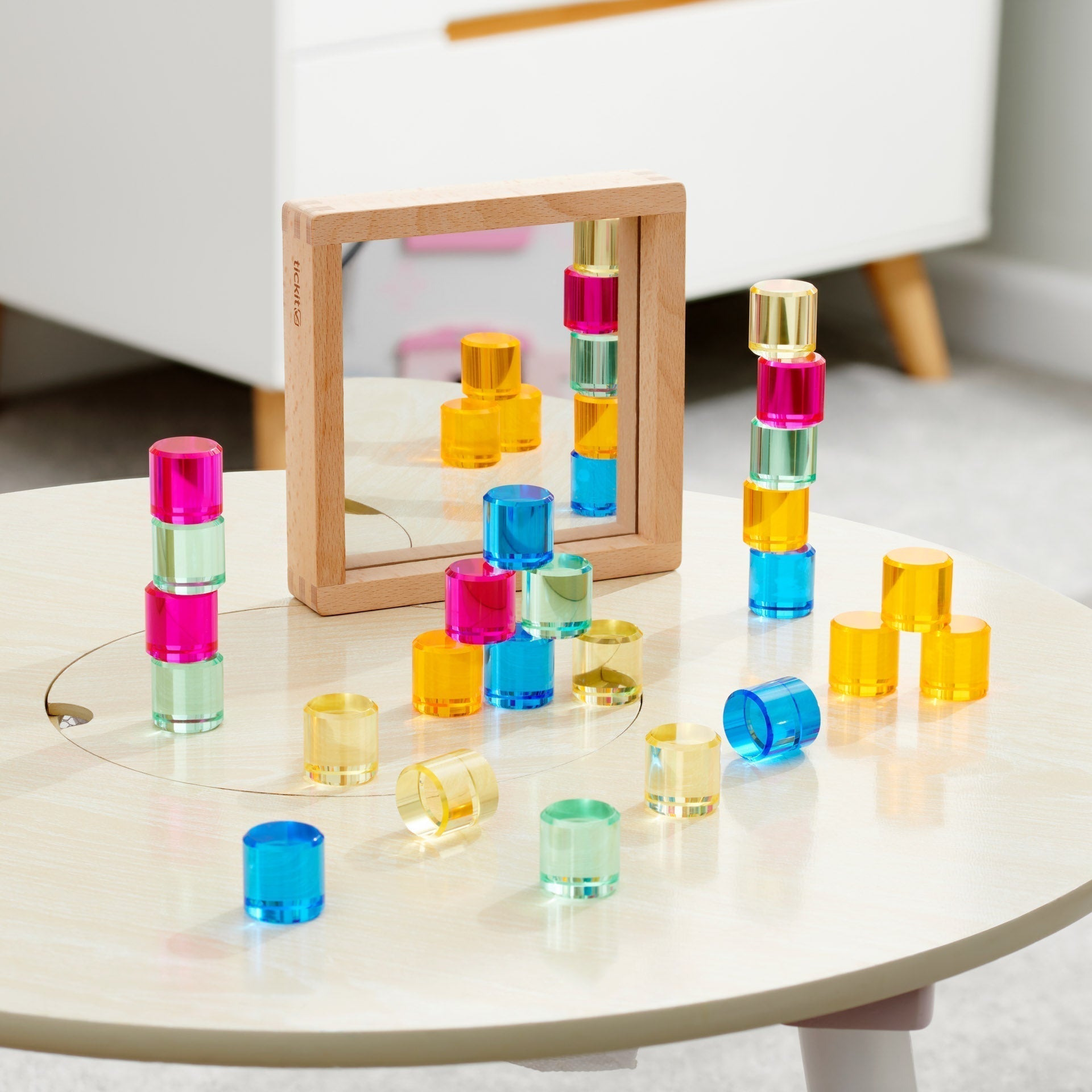 Colorful transparent building blocks stacked on a round table with a mirror in the background.