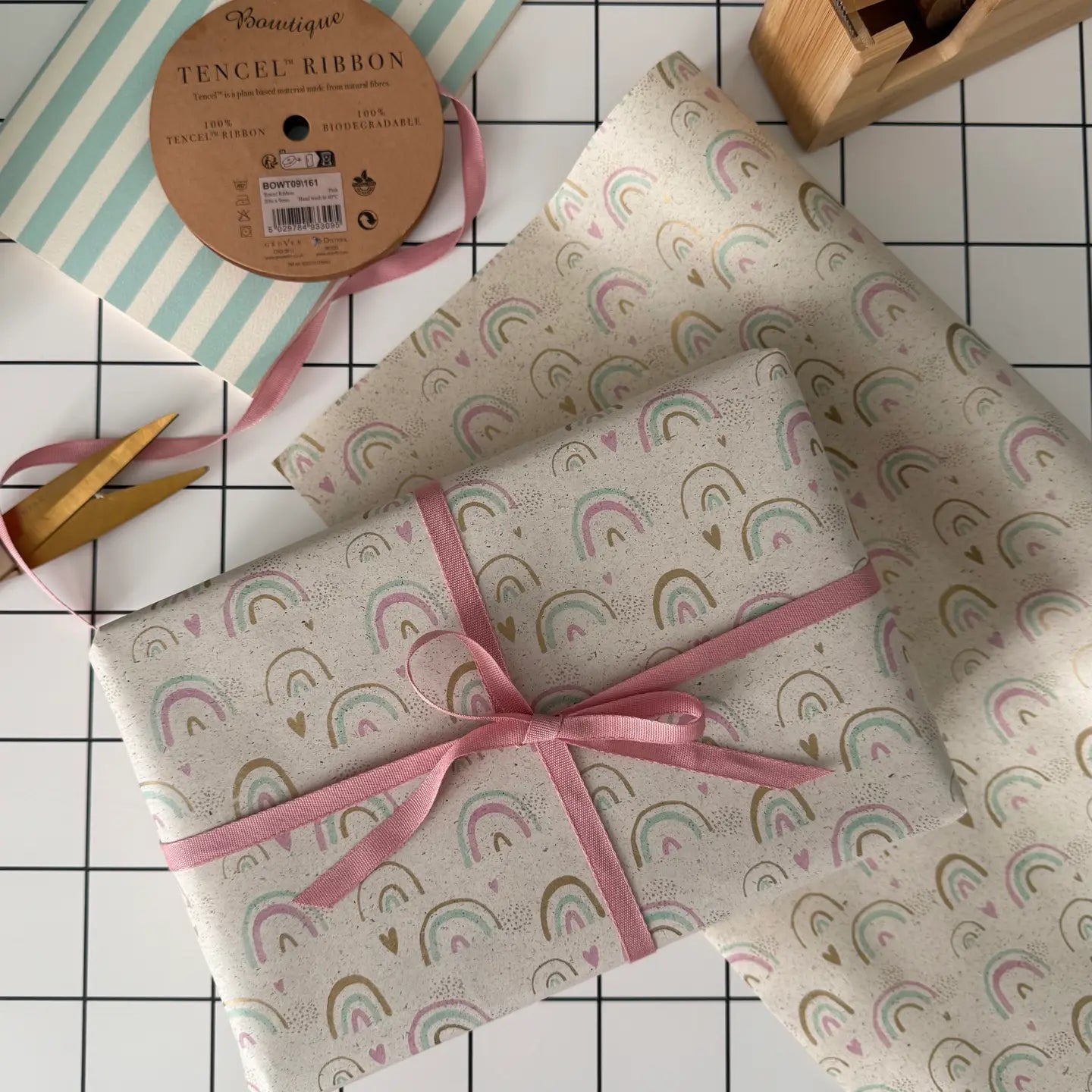 Present with rainbow pattern and pink ribbon on a checkered surface