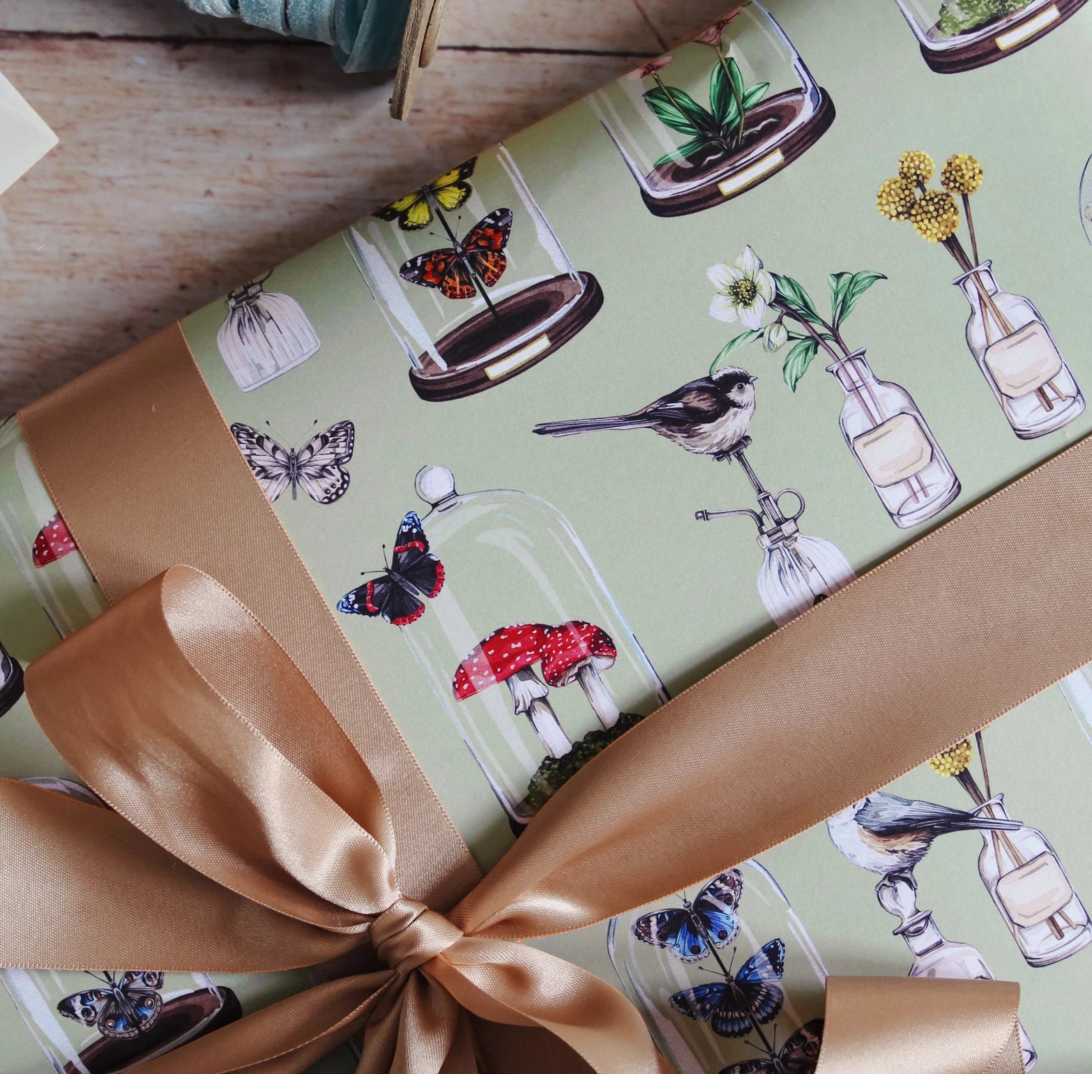 Gift wrapped in paper with nature-themed design and a brown ribbon.