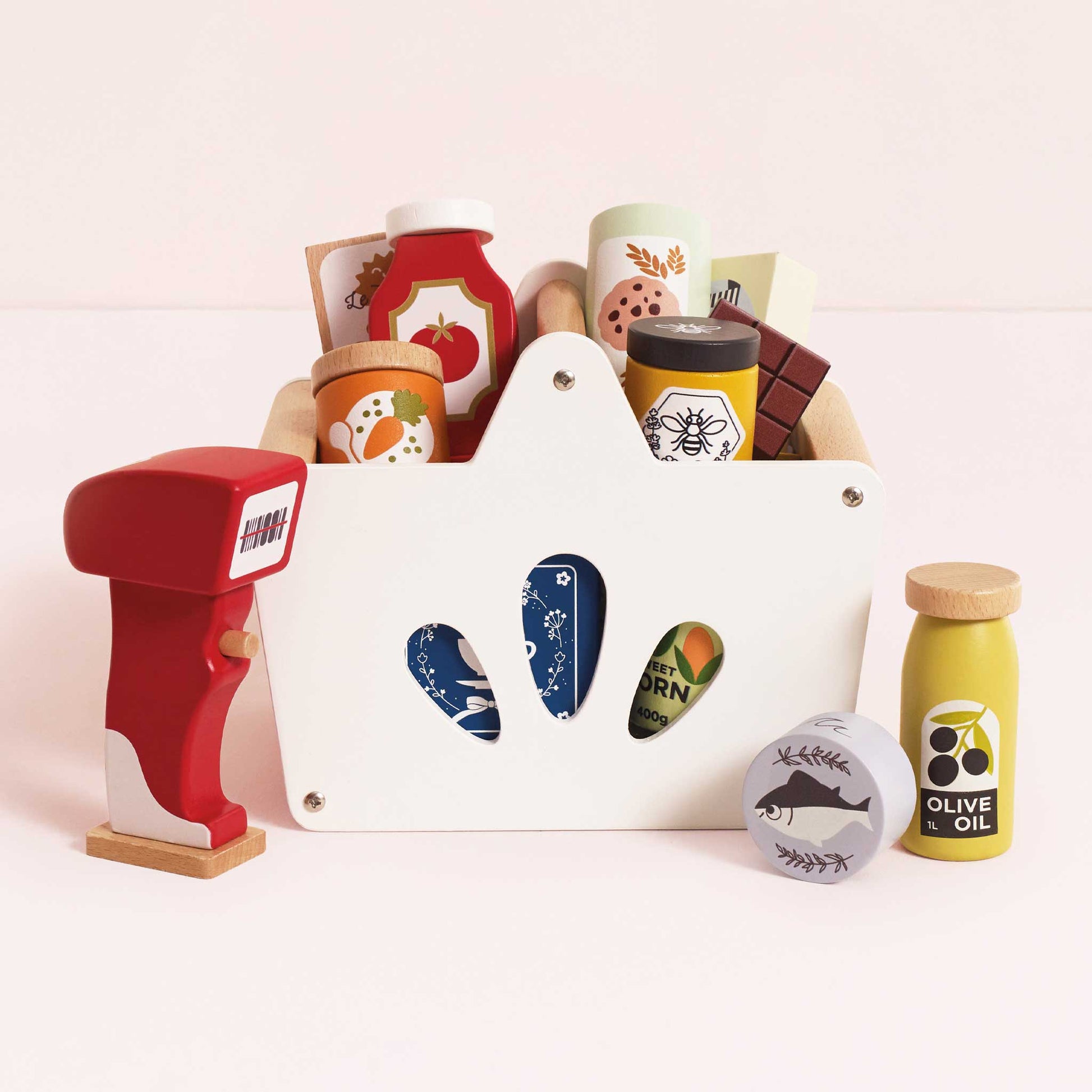 Set of toy kitchen items including a white basket, red cash register, and various toy food containers on a light pink background.