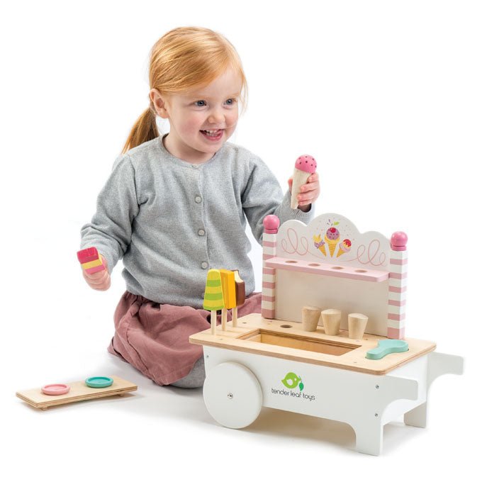 Child playing with a wooden toy kitchen set on a white background