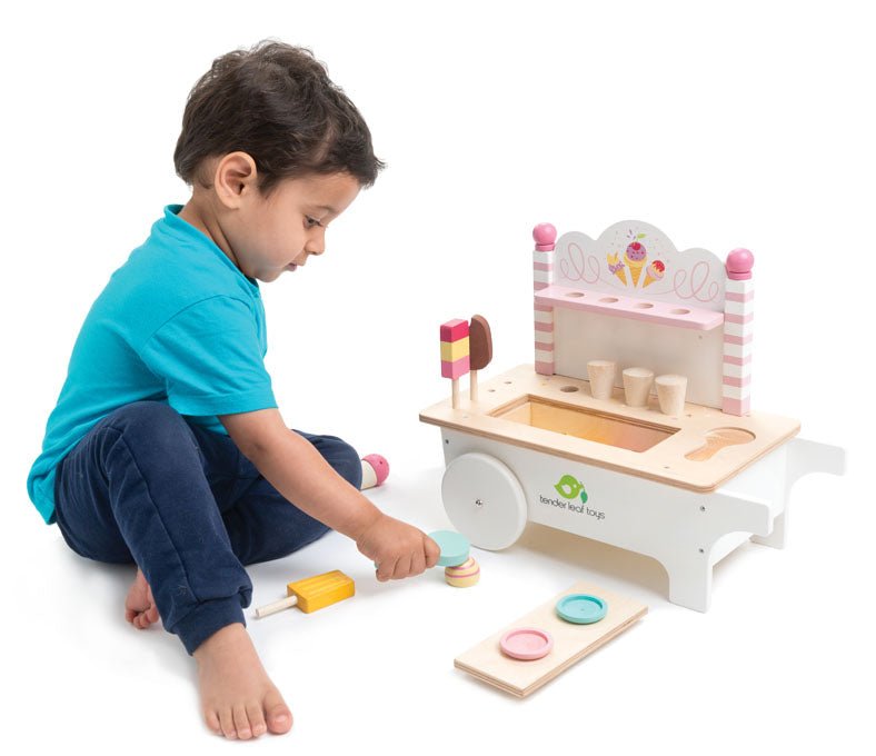 Child playing with a wooden toy kitchen set on a white background