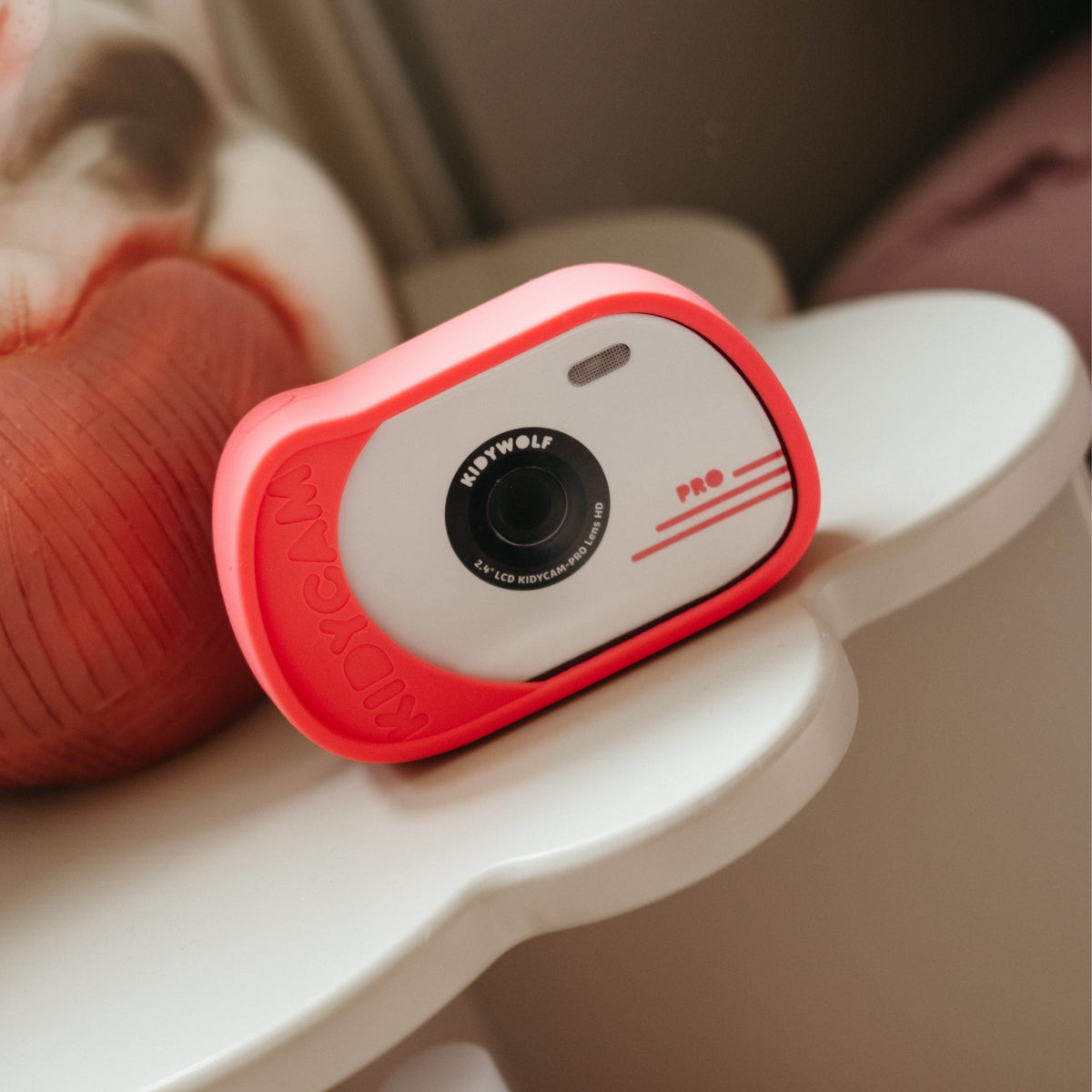 Small red and white camera on a white surface with a blurred background