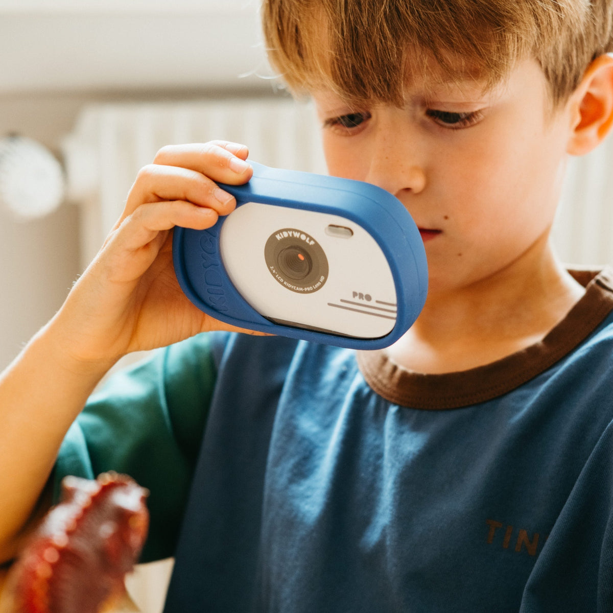 Child holding a blue and white toy camera close to their face
