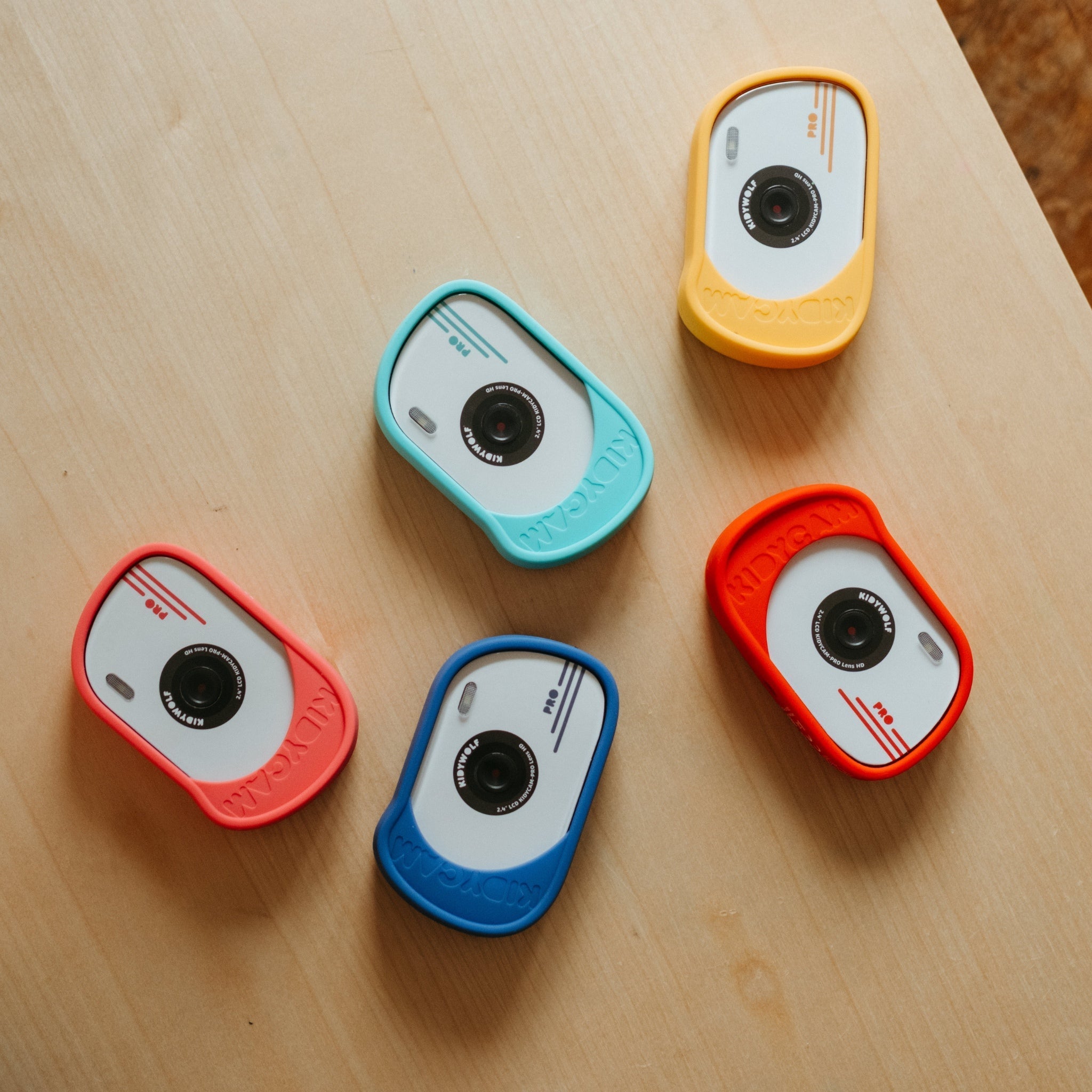 Five colorful camera-shaped objects on a wooden surface