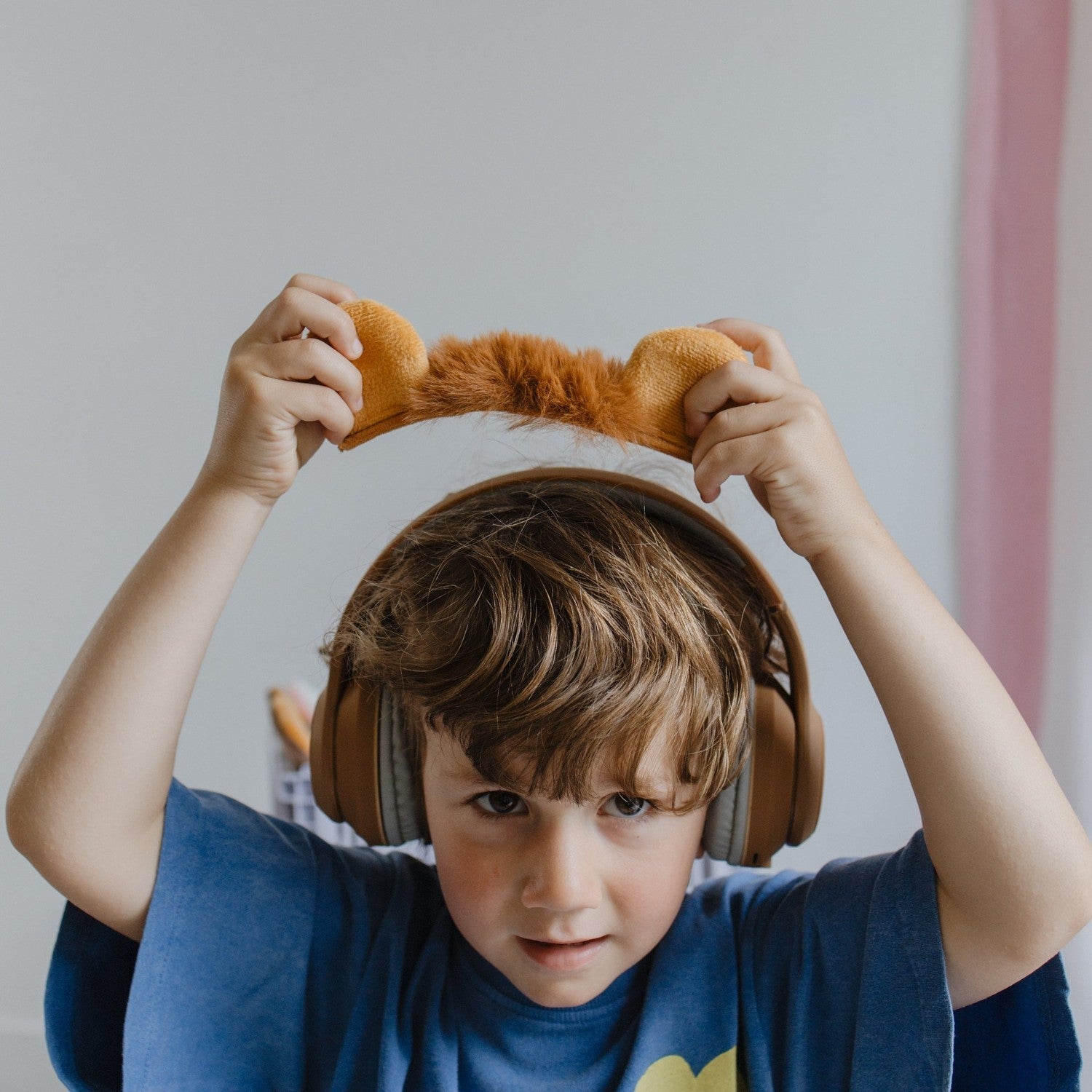 Child wearing large headphones with animal ears, indoors.