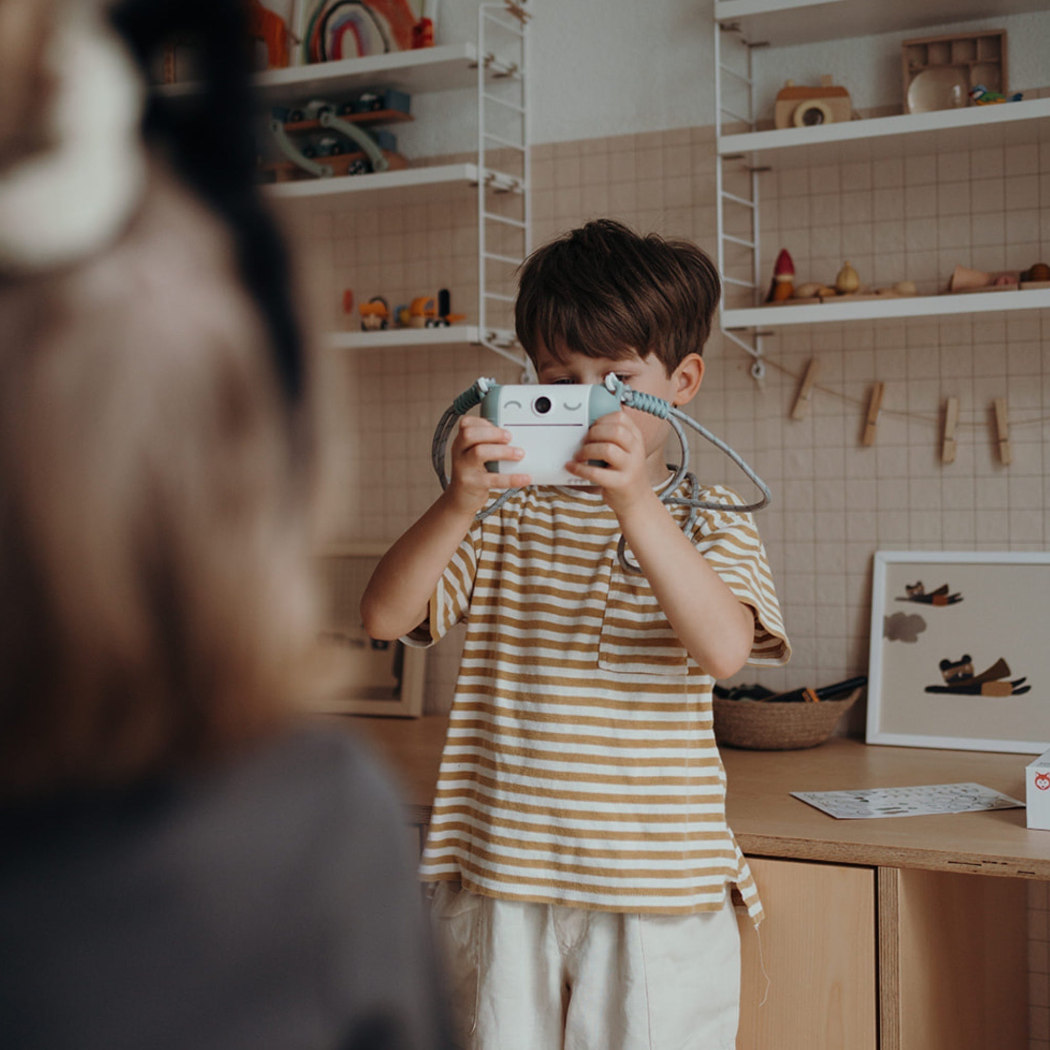 Child holding a camera in a kitchen setting