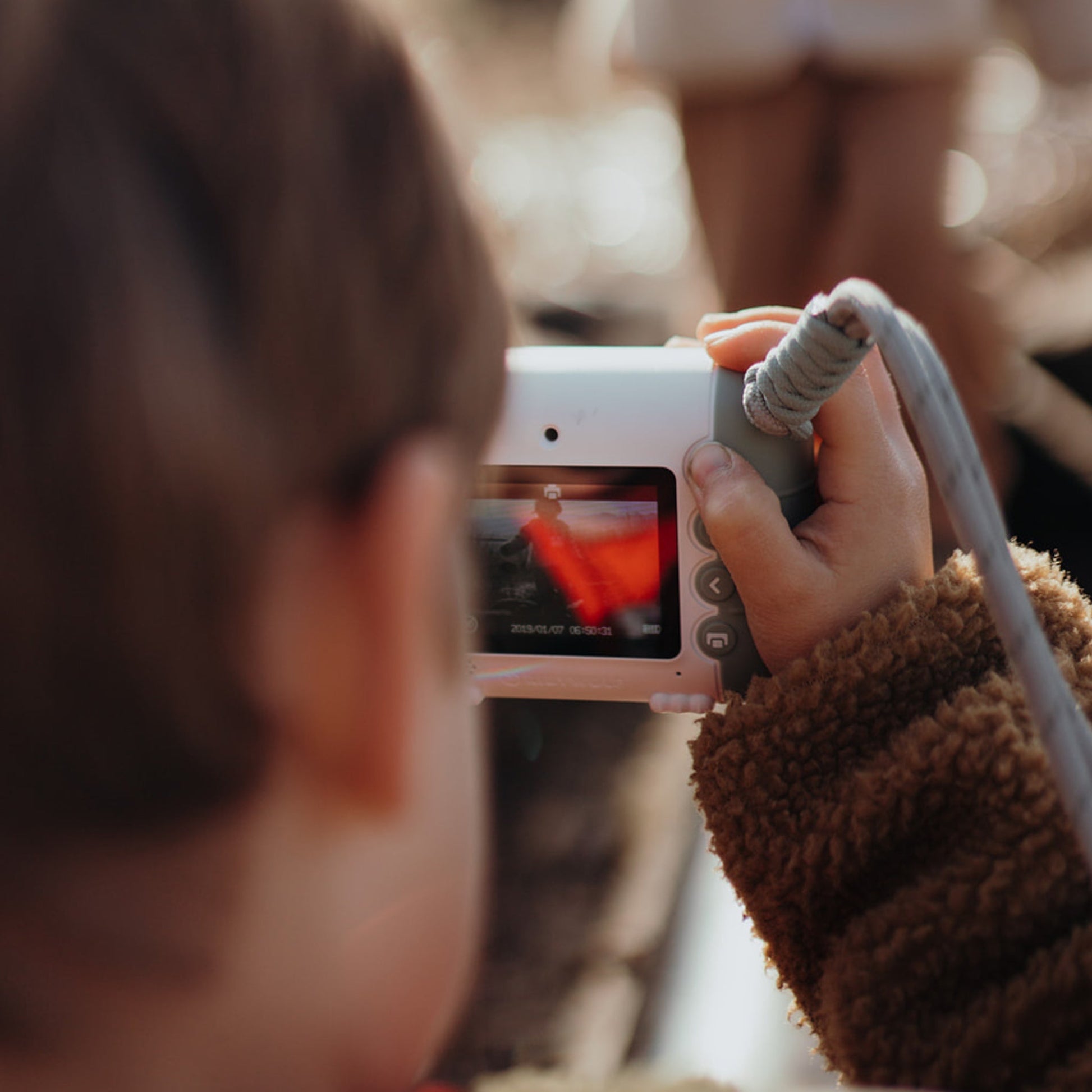 Person holding a small camera with a blurred background