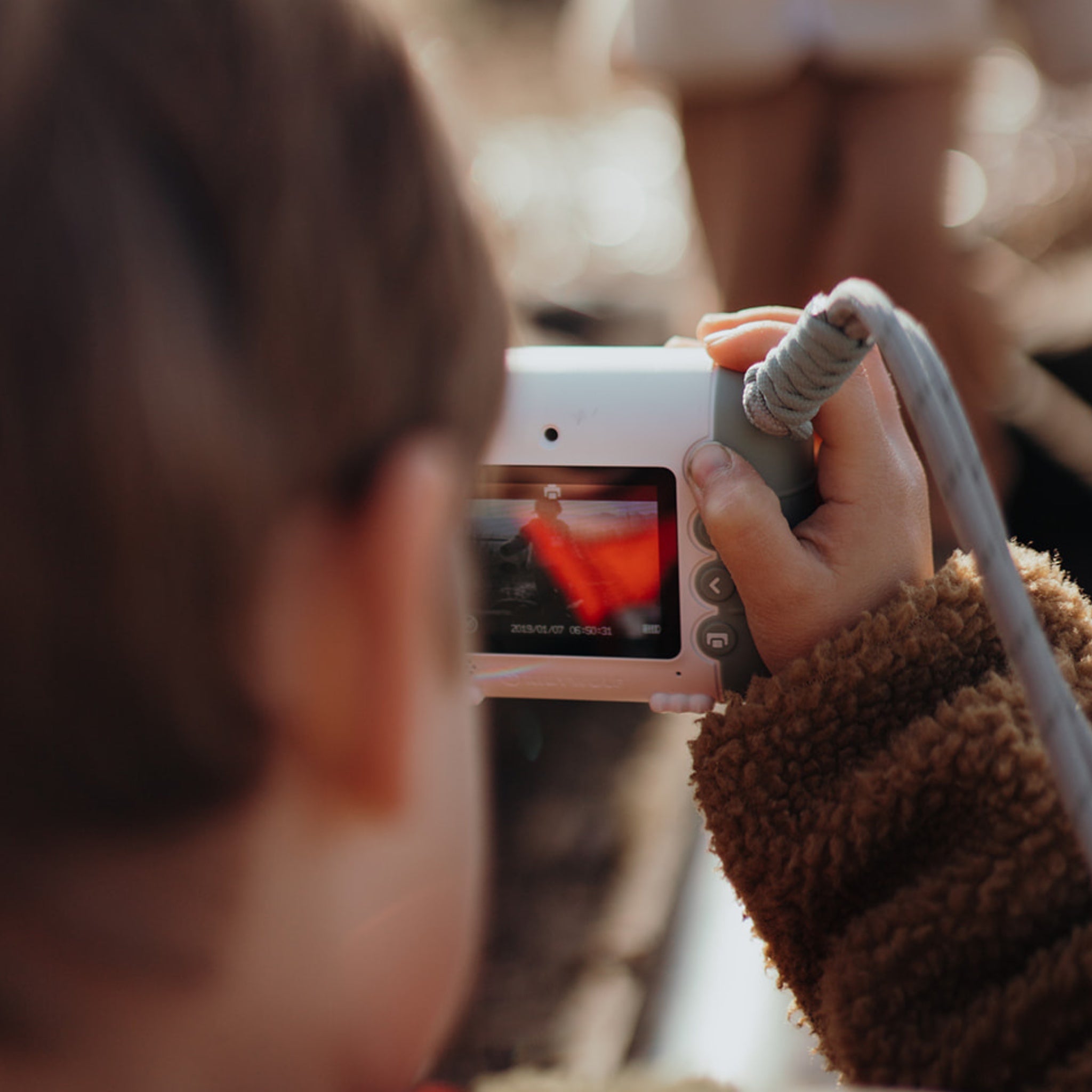 Person holding a small camera with a blurred background