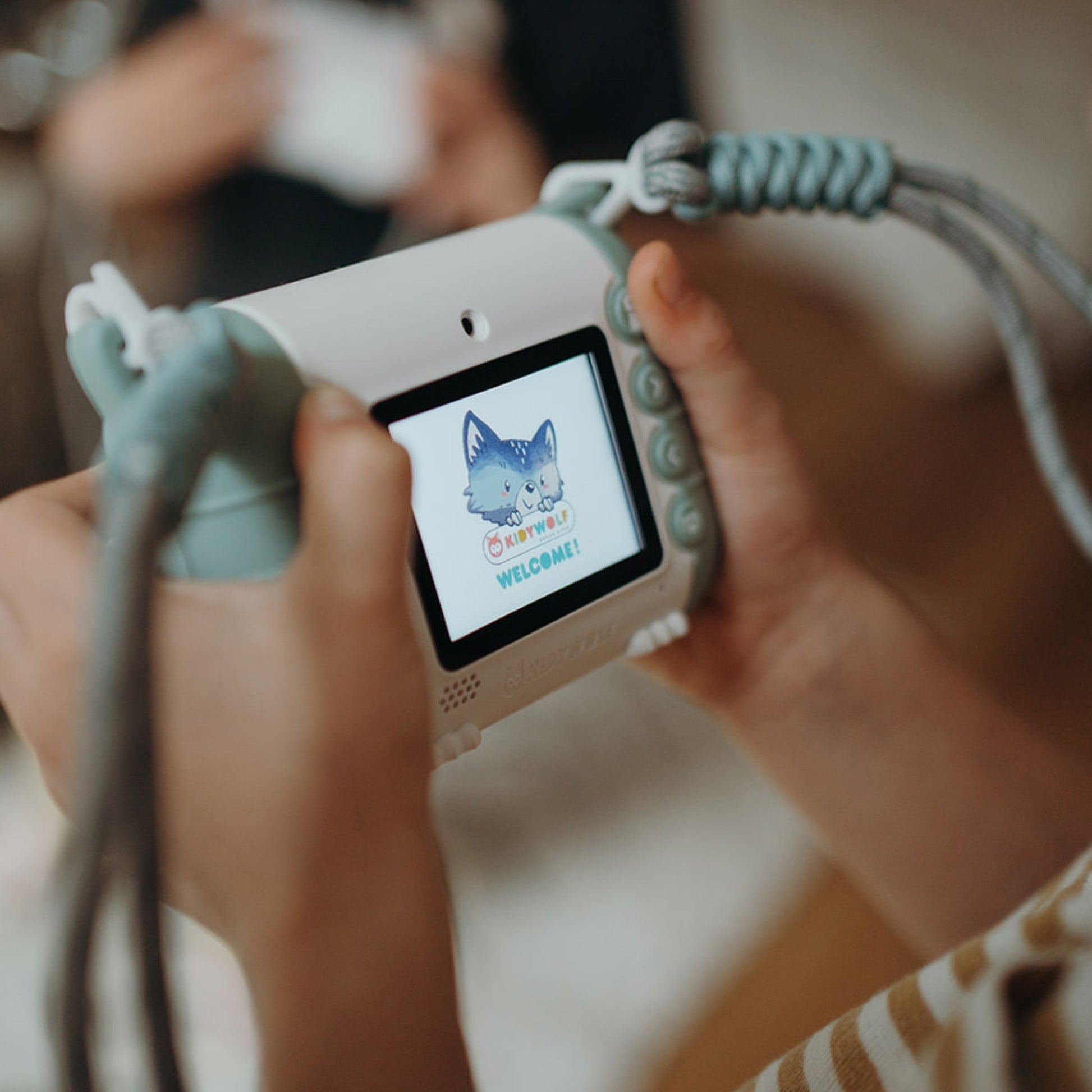 Child holding a small electronic device with a screen displaying a cartoon cat and text.