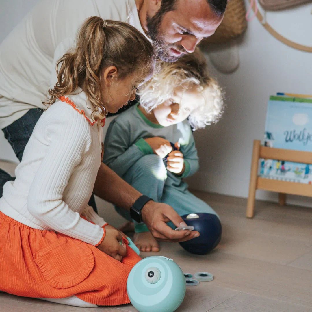 Father and two children playing with a toy on the floor