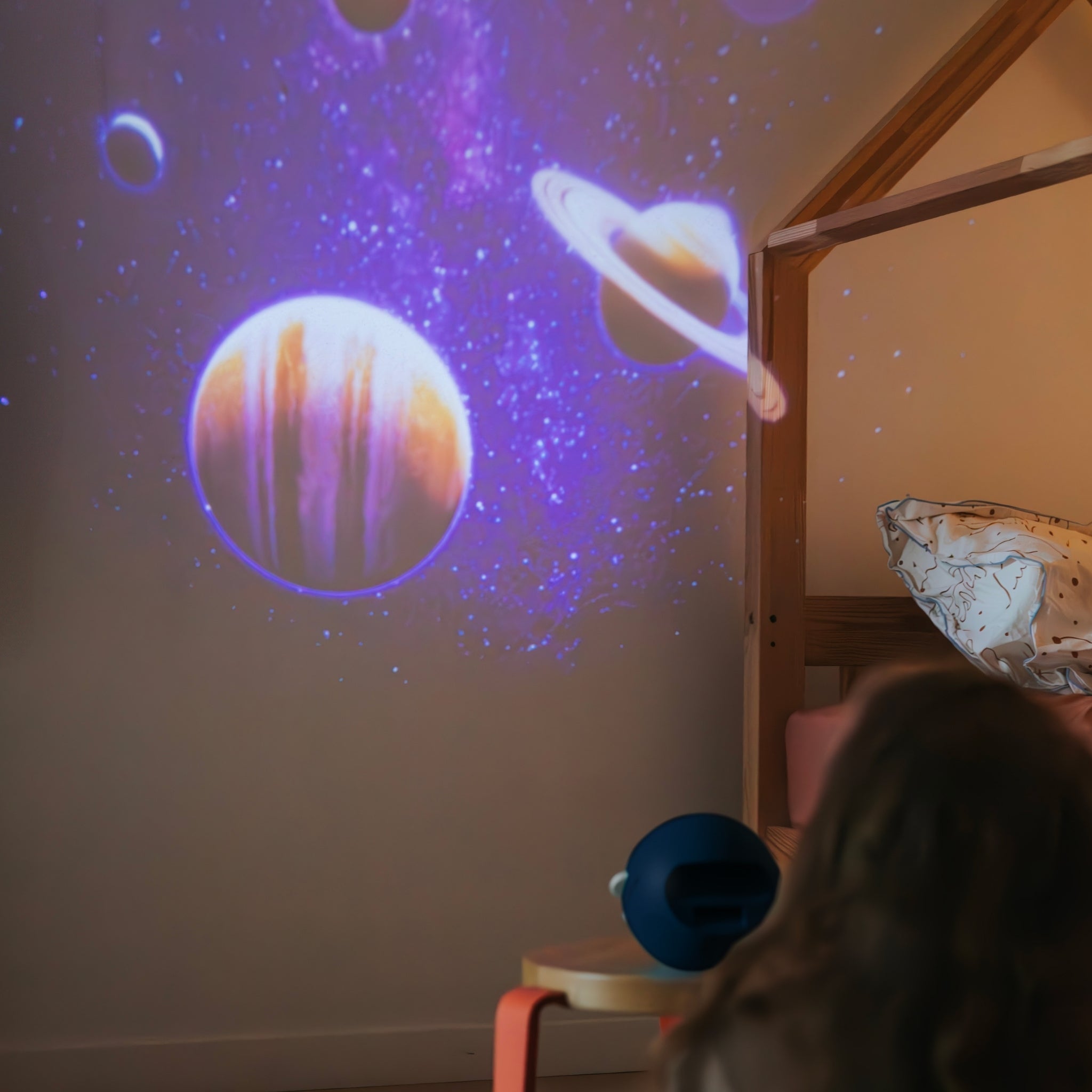 Projection of celestial bodies on a wall with a child looking at it.