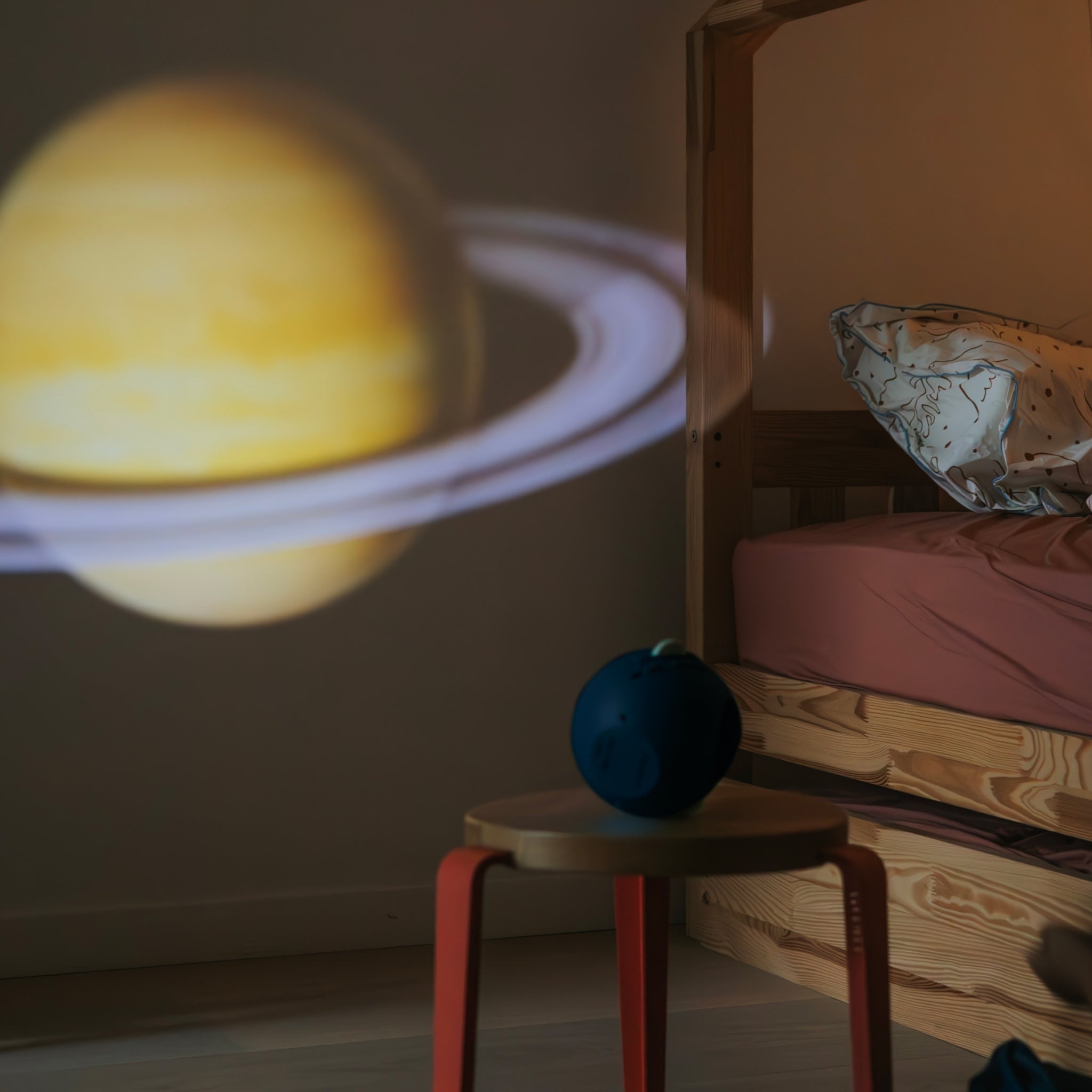 Projection of a planet on a wall with a wooden stool and cushion in the foreground.