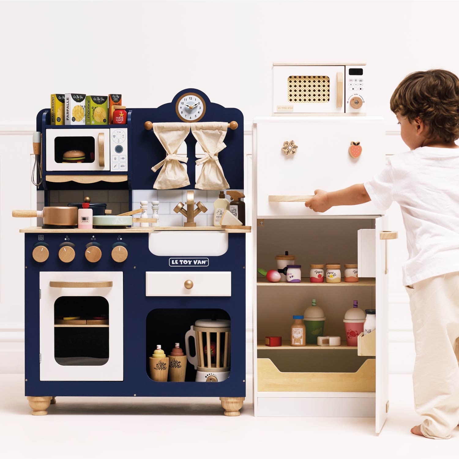 Child playing with a toy kitchen set on a white background