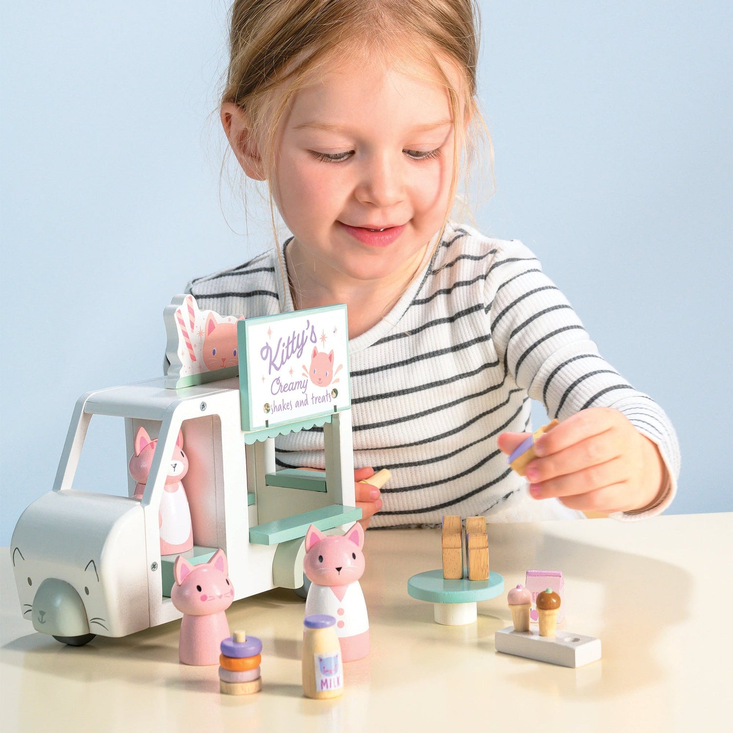 Child playing with a toy set on a table against a light blue background