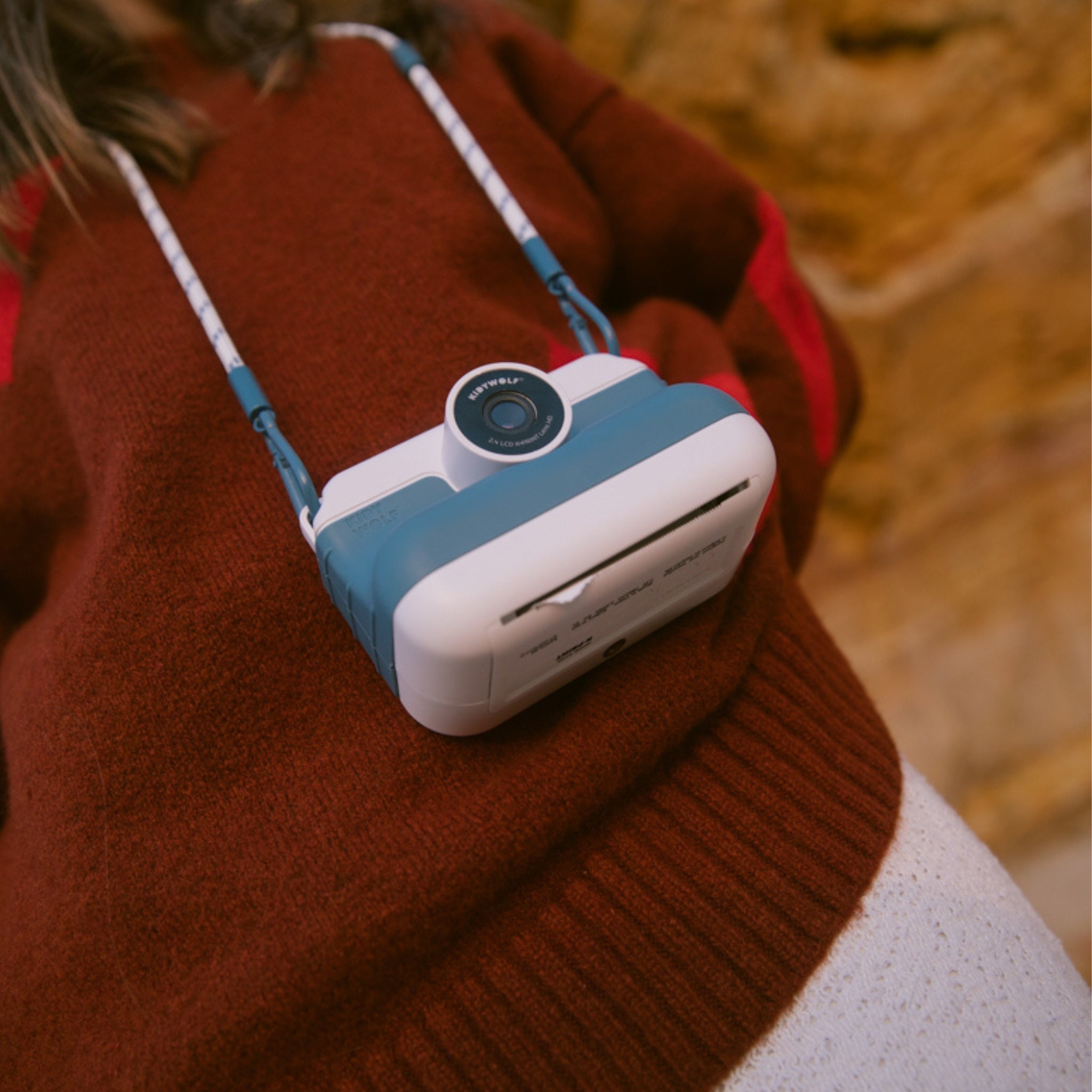 Small blue and white camera attached to a person wearing a brown sweater.