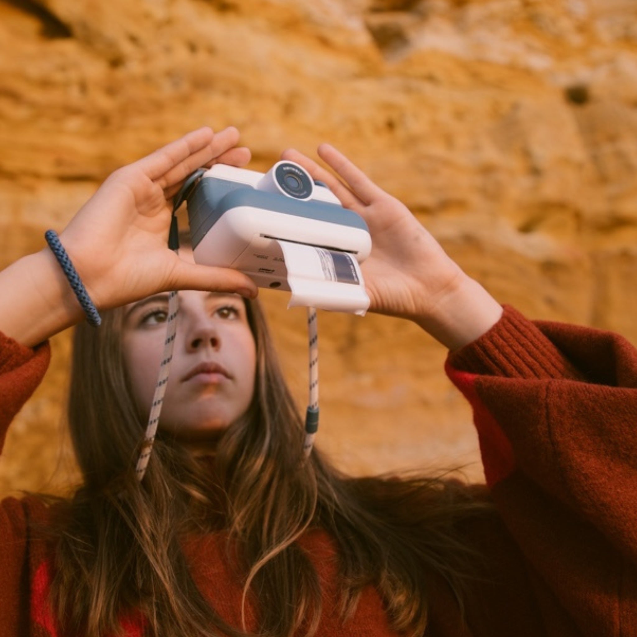 Person holding a vintage camera against a warm-toned natural background