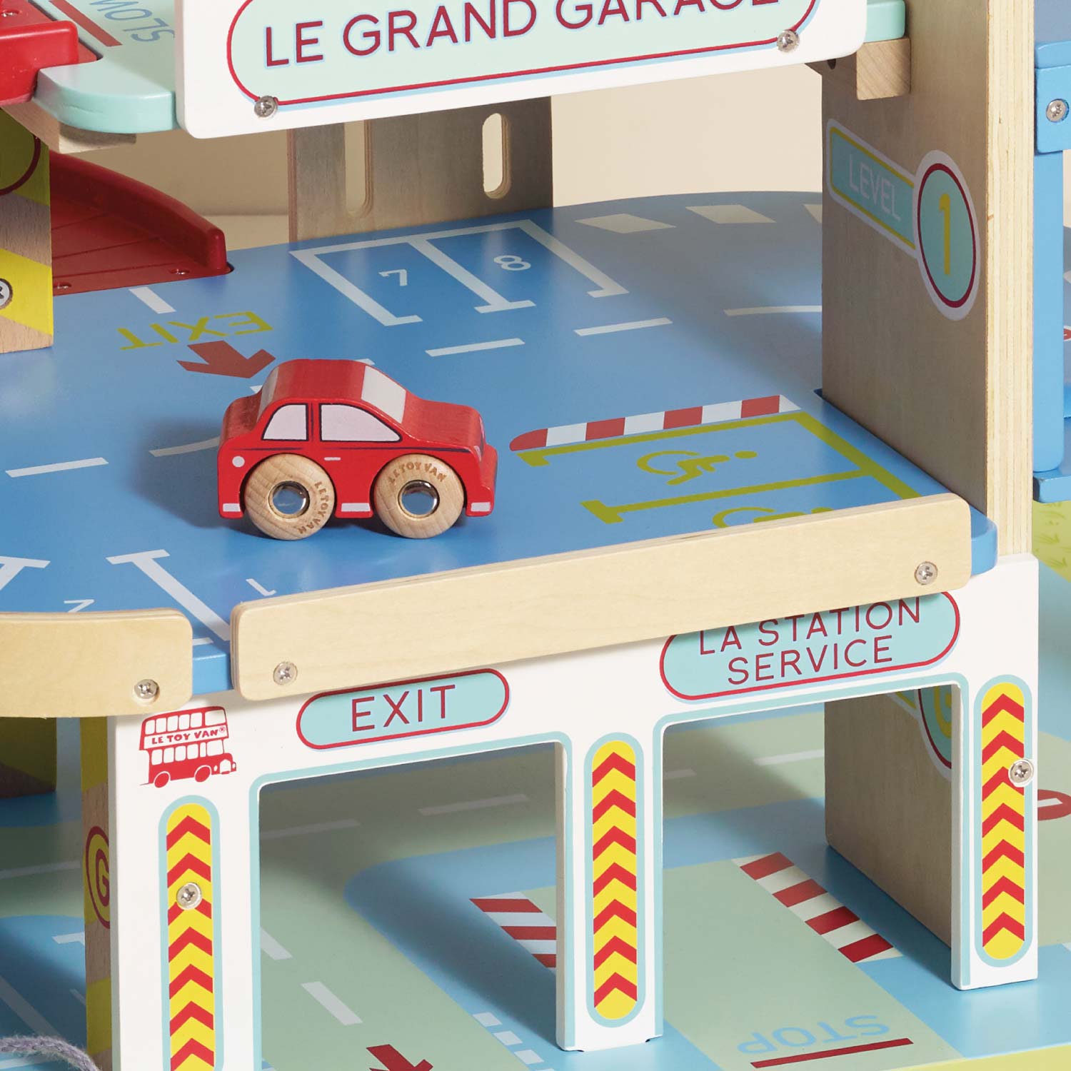 Toy garage set with a red car on a blue platform, featuring signs and road markings.