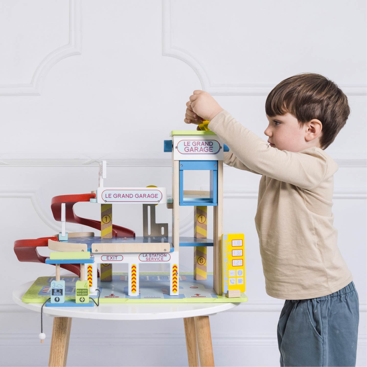 Child playing with a toy garage set on a white background