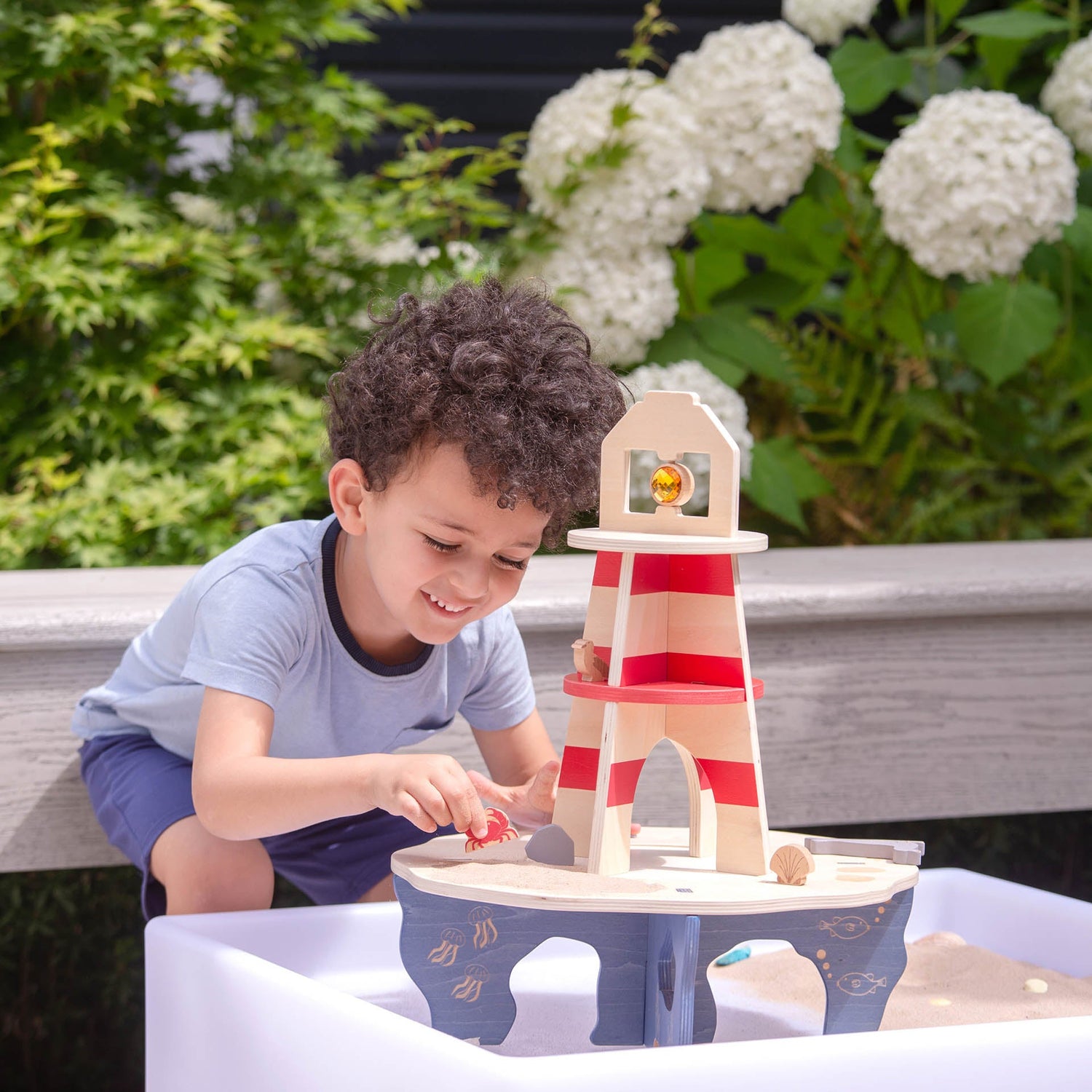 Child playing with a wooden lighthouse toy outdoors