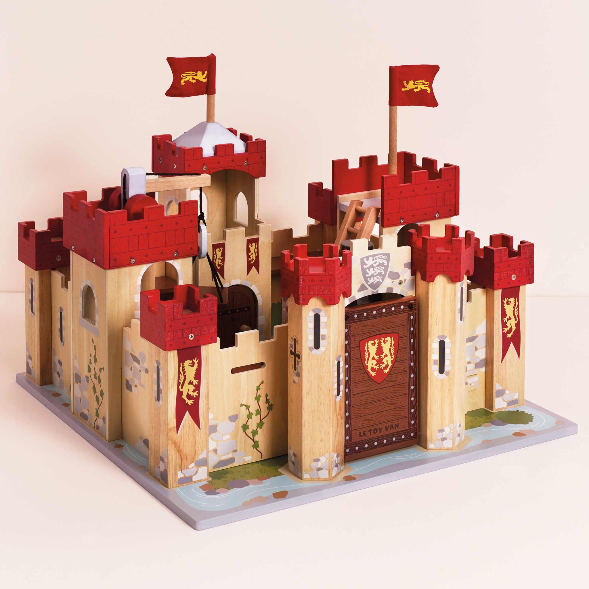 Wooden toy castle with red towers and flags on a beige background