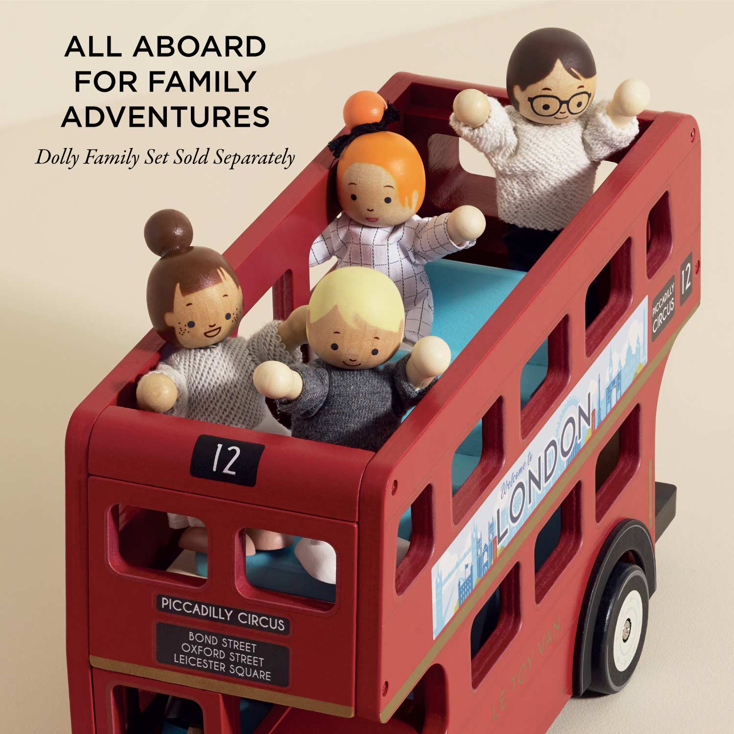 Toy red double-decker bus with dolls inside on a beige background