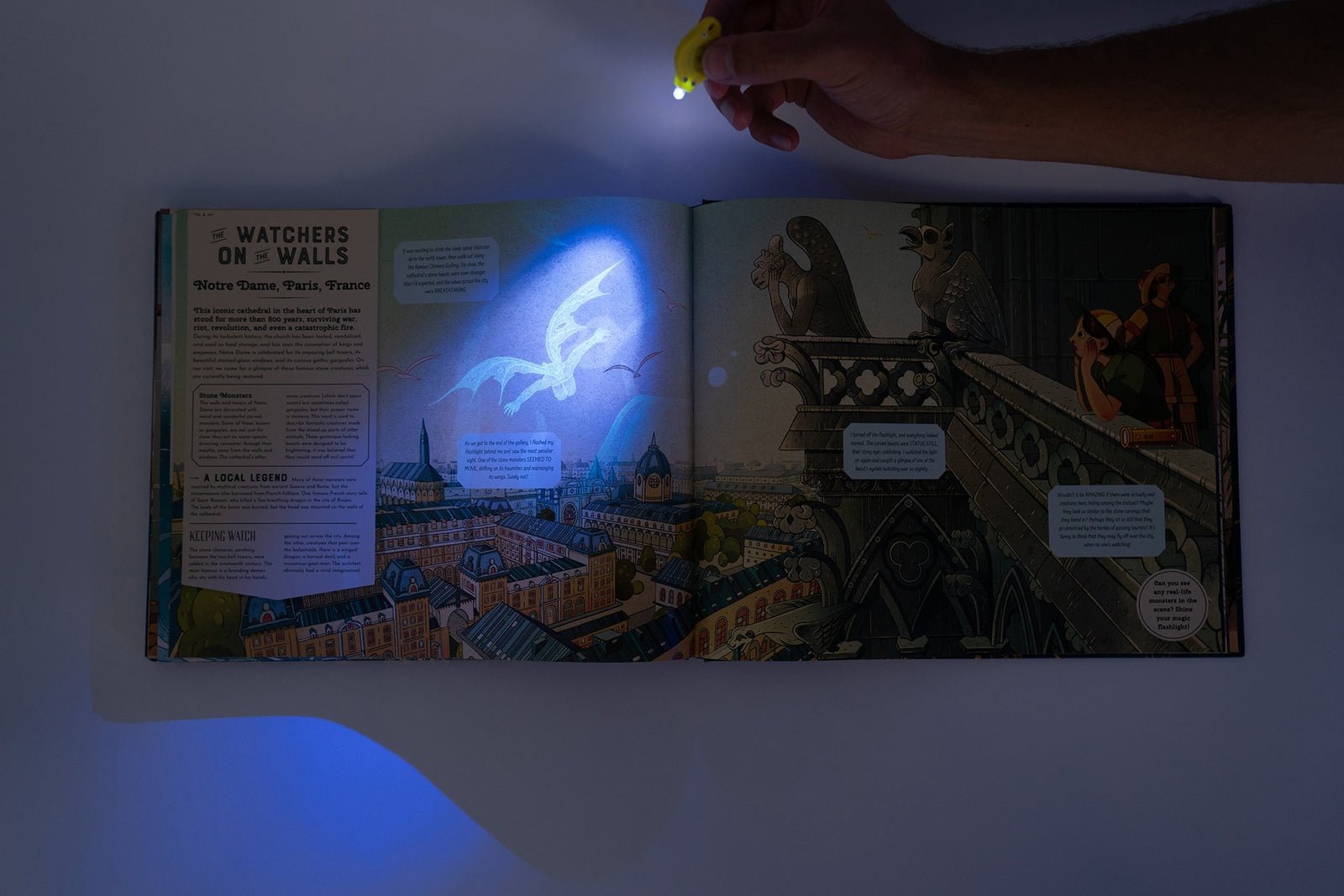 Open book with glowing illustration of a ghost on a balcony, held by a hand with a flashlight.