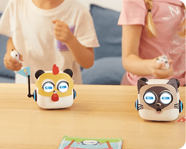 Three cartoon-like robot toys on a table with children in the background.