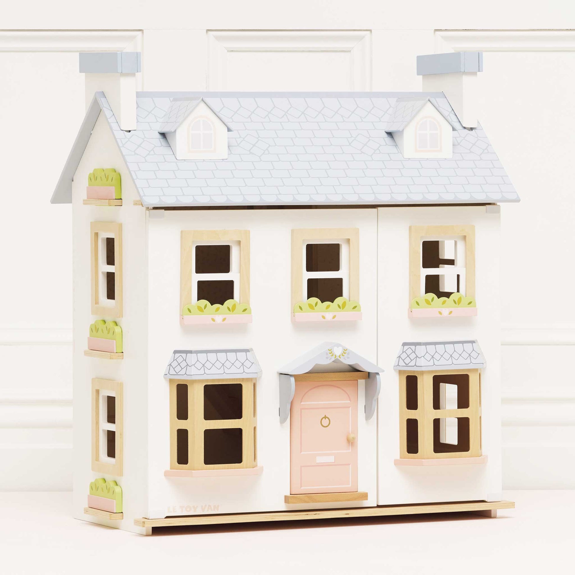 Toy dollhouse with a light blue roof and pink door on a white background