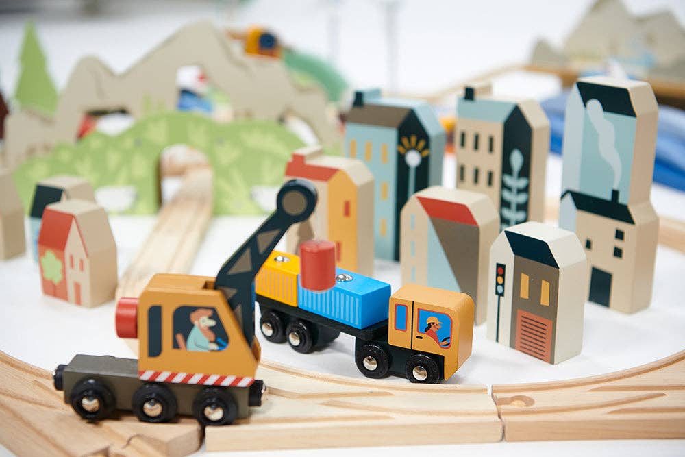 Wooden toy train set with buildings and trees in the background