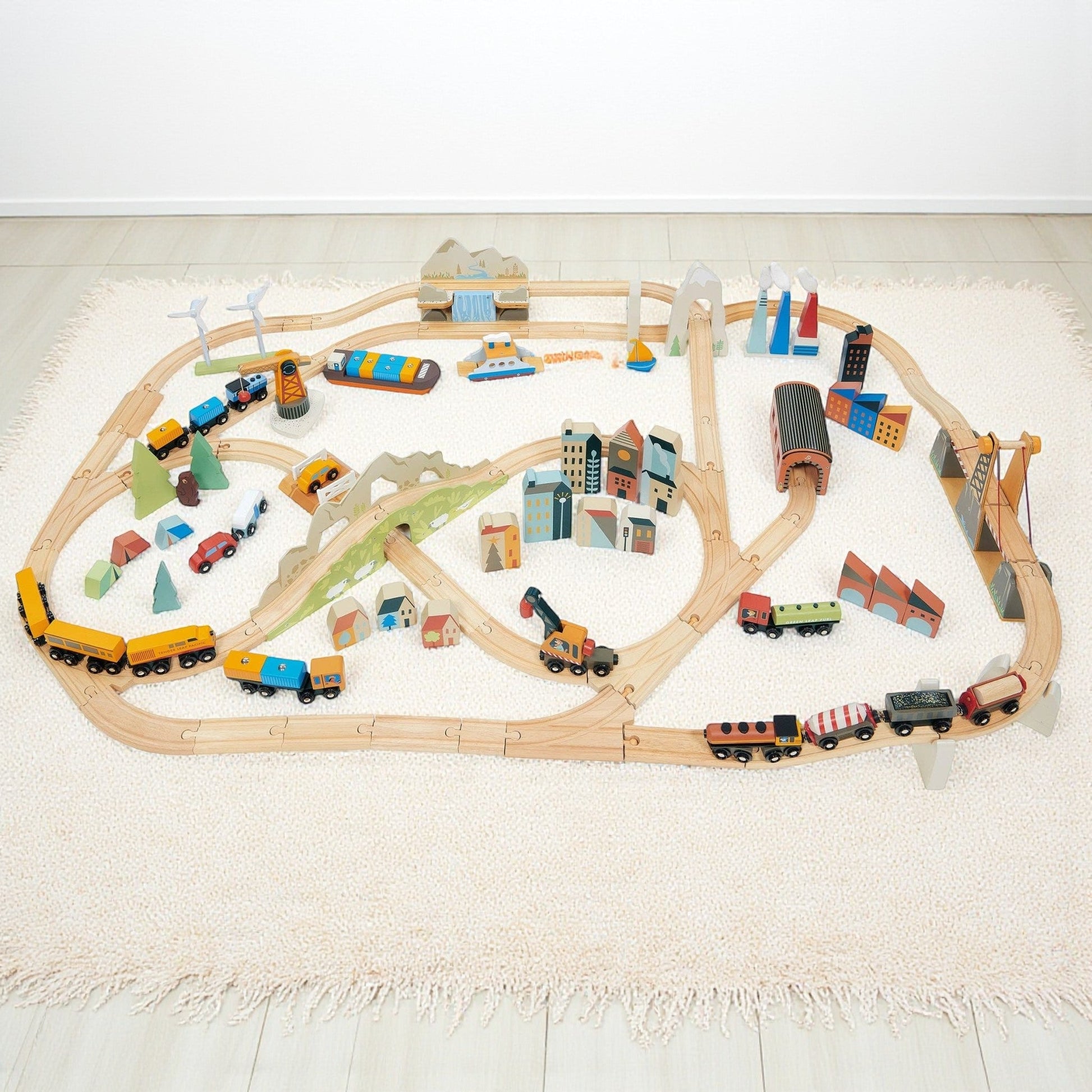 Wooden toy train set with tracks and various train cars on a light surface