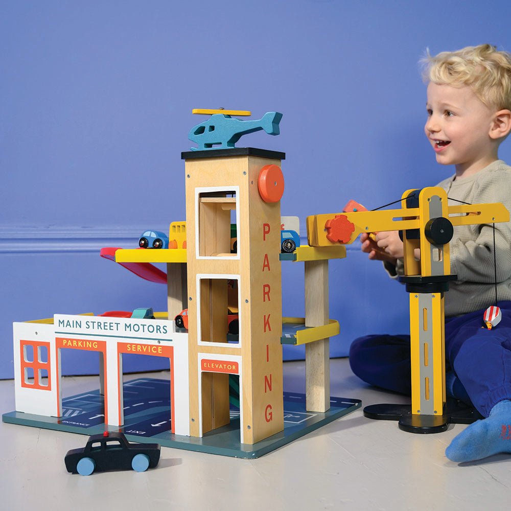 Child playing with a toy parking garage set against a blue background