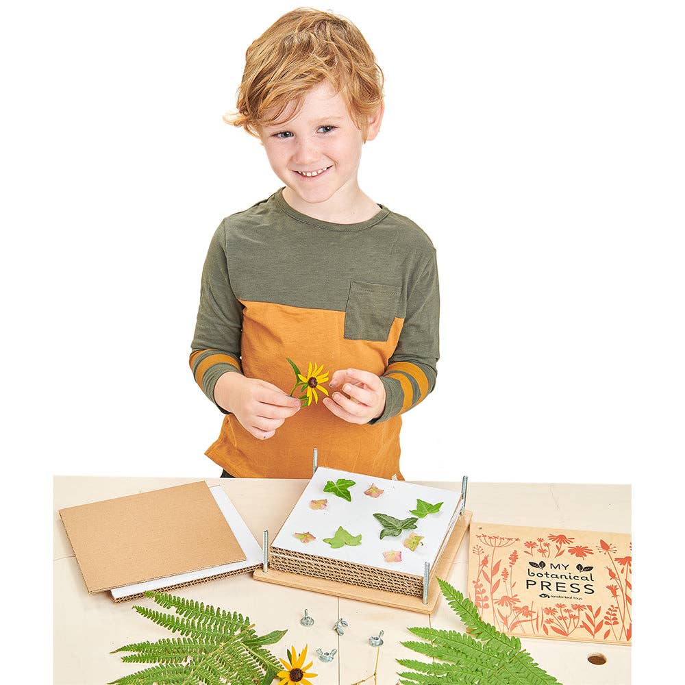 Child holding a sunflower with a botanical press and nature-themed items on a table
