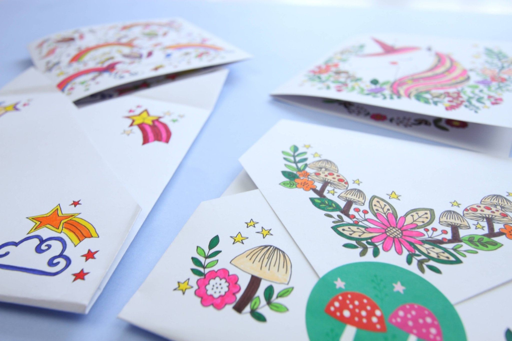 Collection of colorful greeting cards with various designs on a light blue background