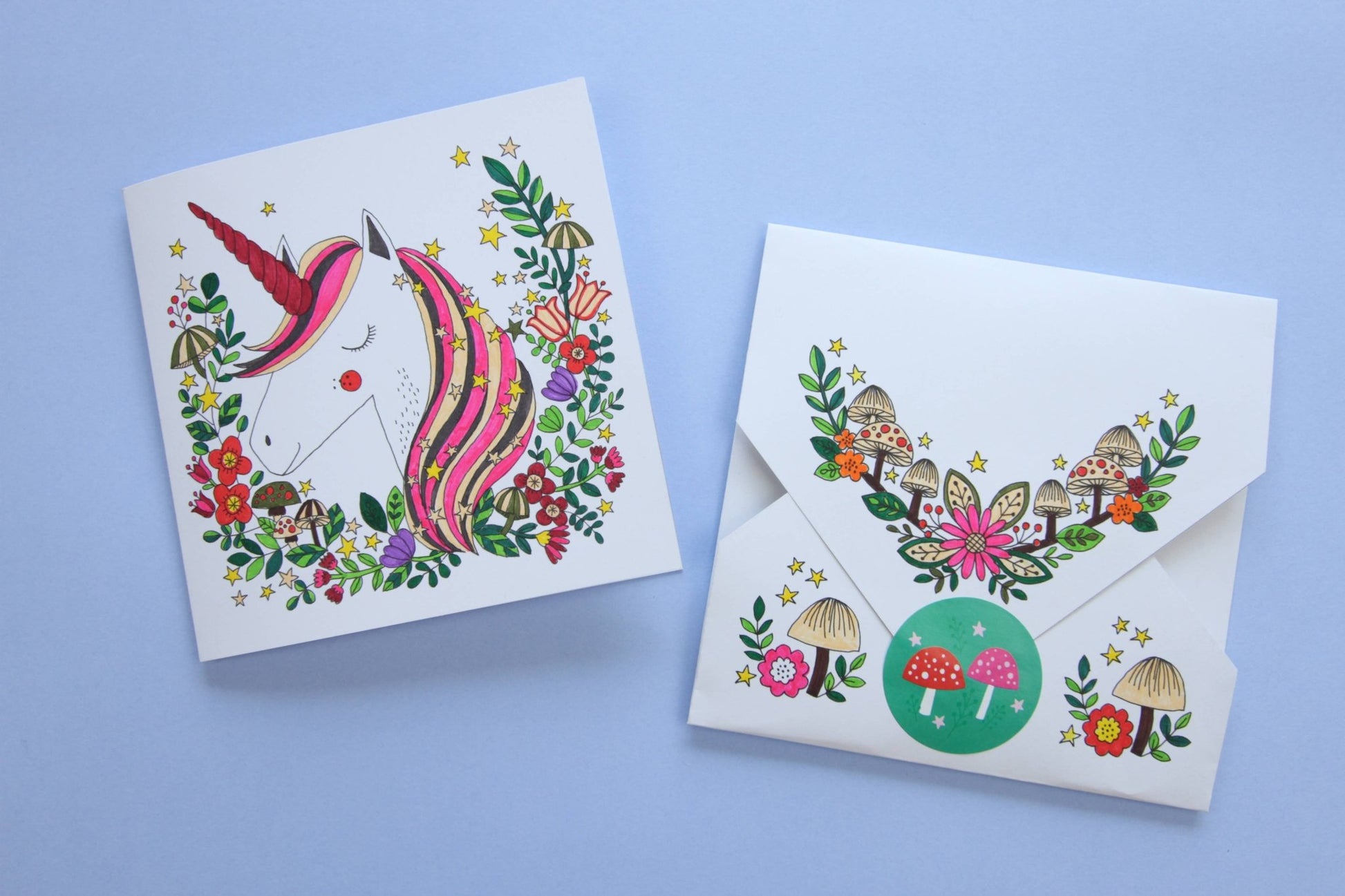 Greeting card with unicorn design and matching envelope on a blue background