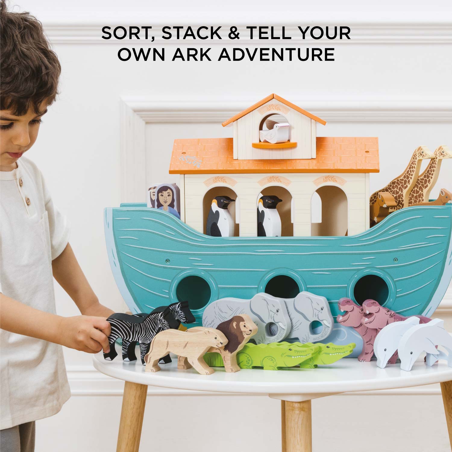 Child playing with a wooden Noah's Ark toy set on a table.