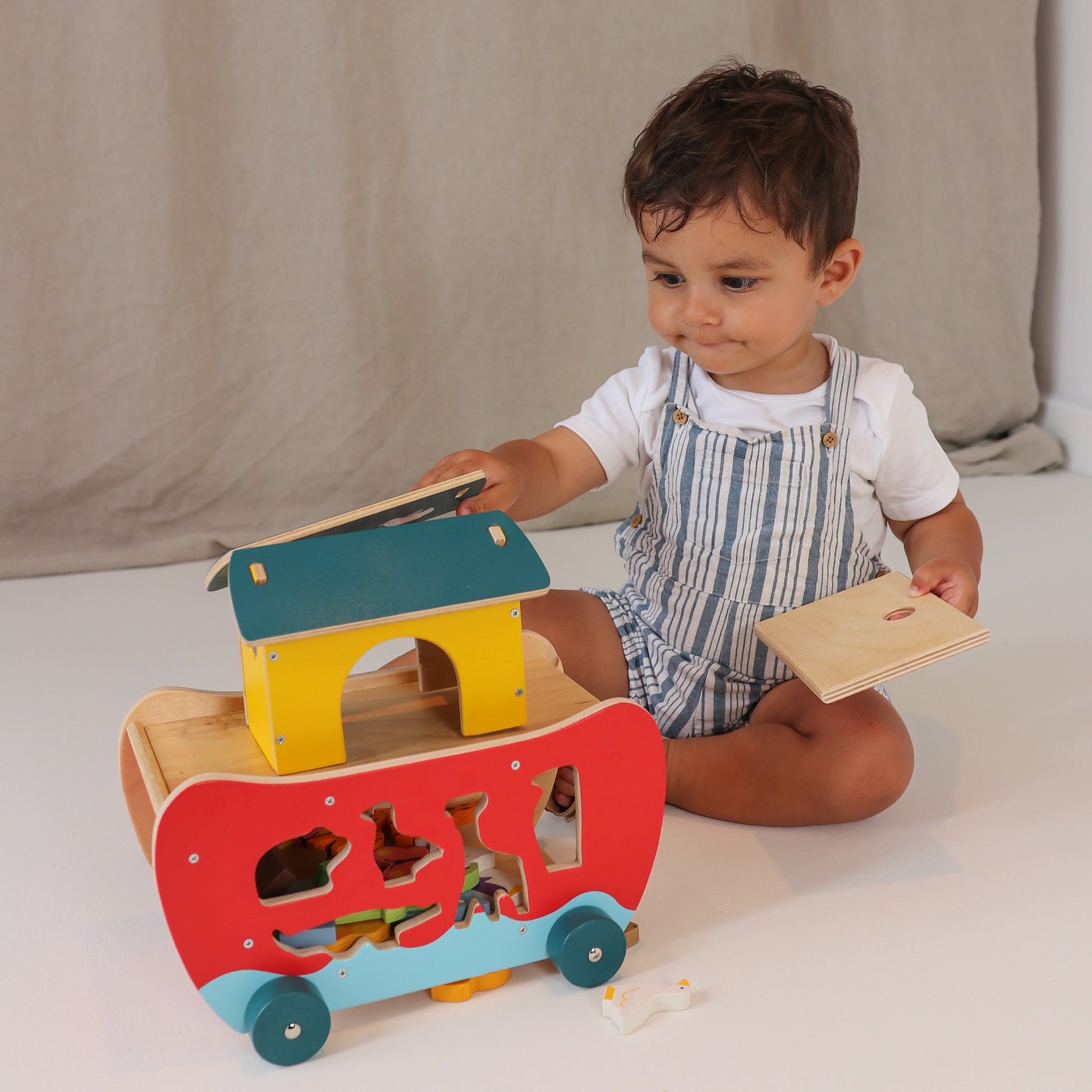 Child playing with a colorful wooden toy on a neutral background