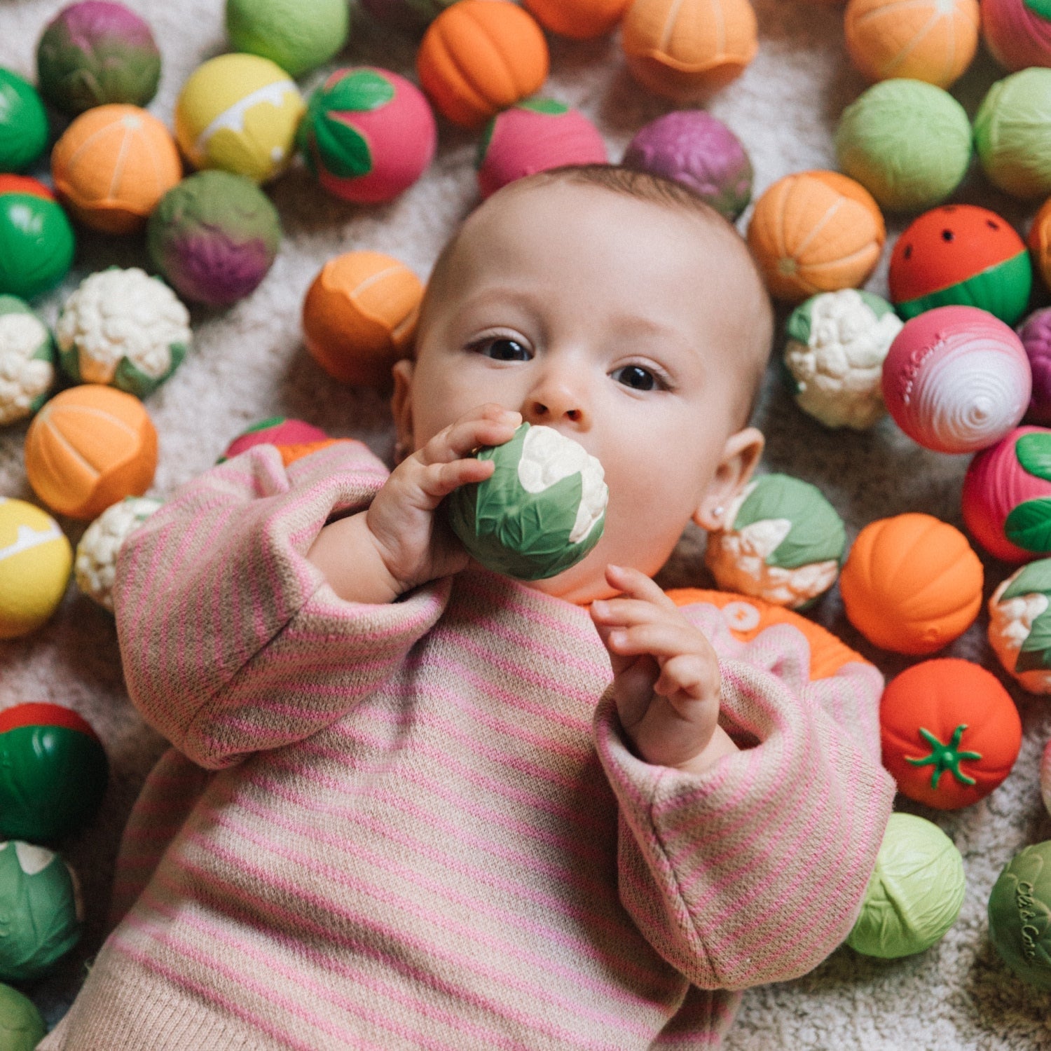 Baby playing with colorful toy balls on a soft surface