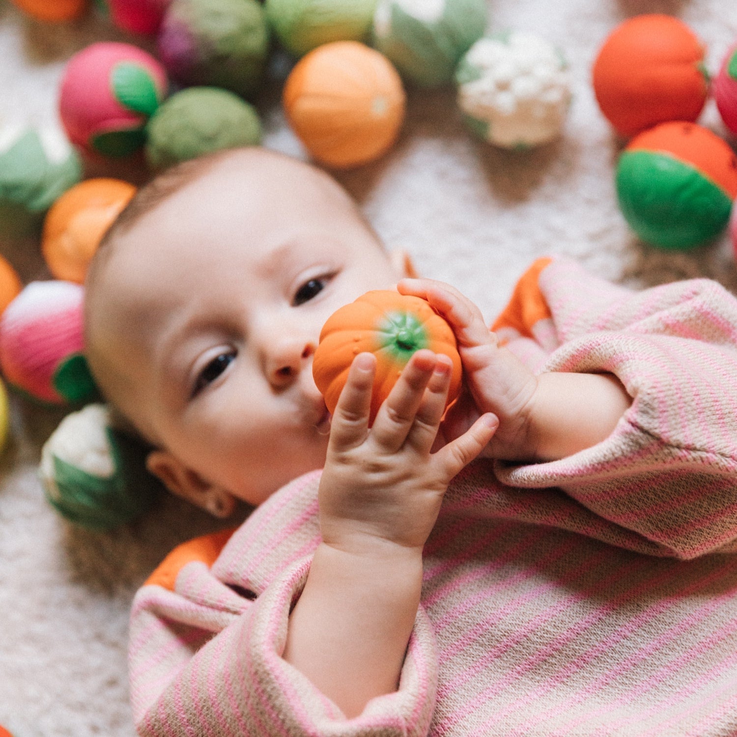 Baby playing with colorful soft toys on a carpet