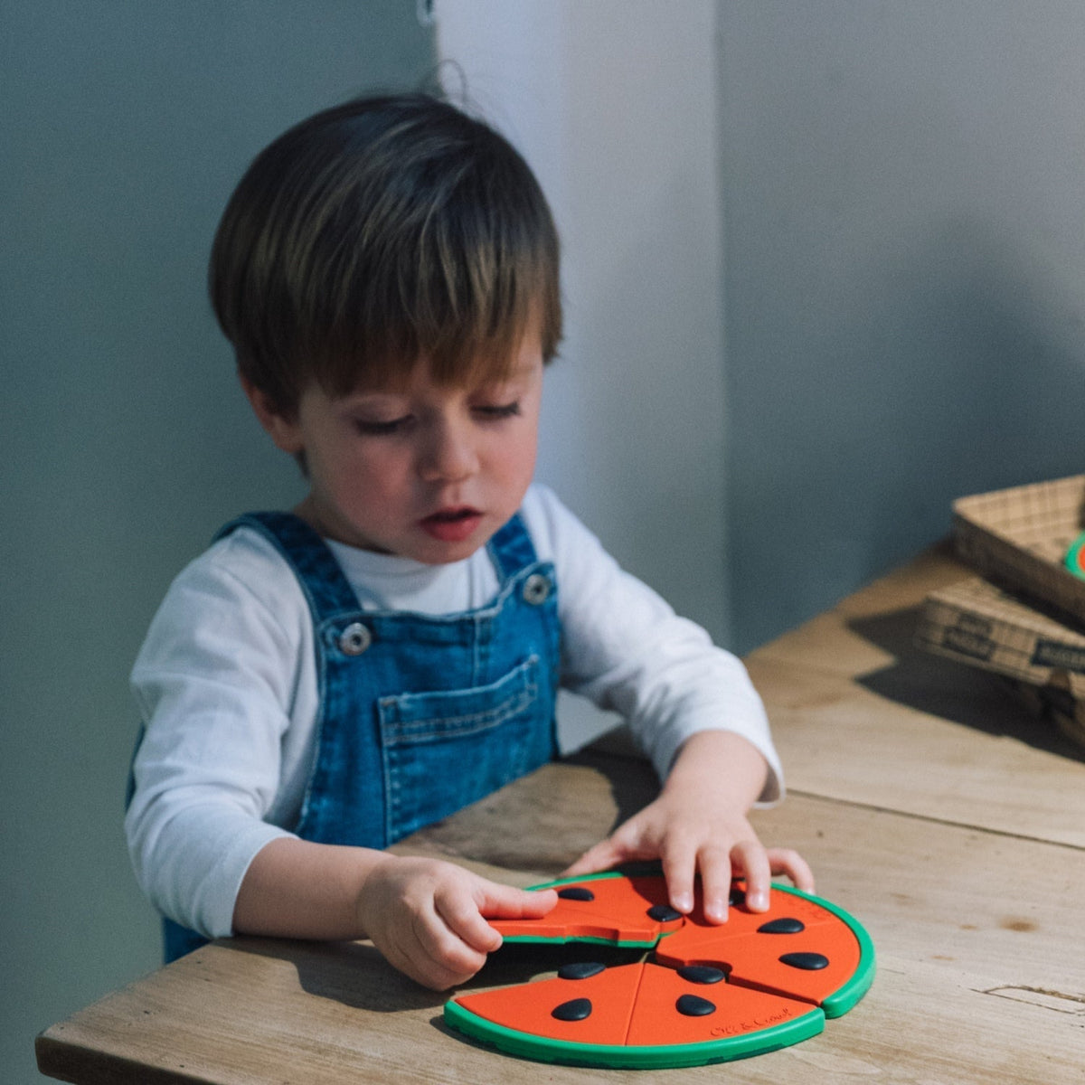 Child playing with a colorful puzzle on a wooden table.