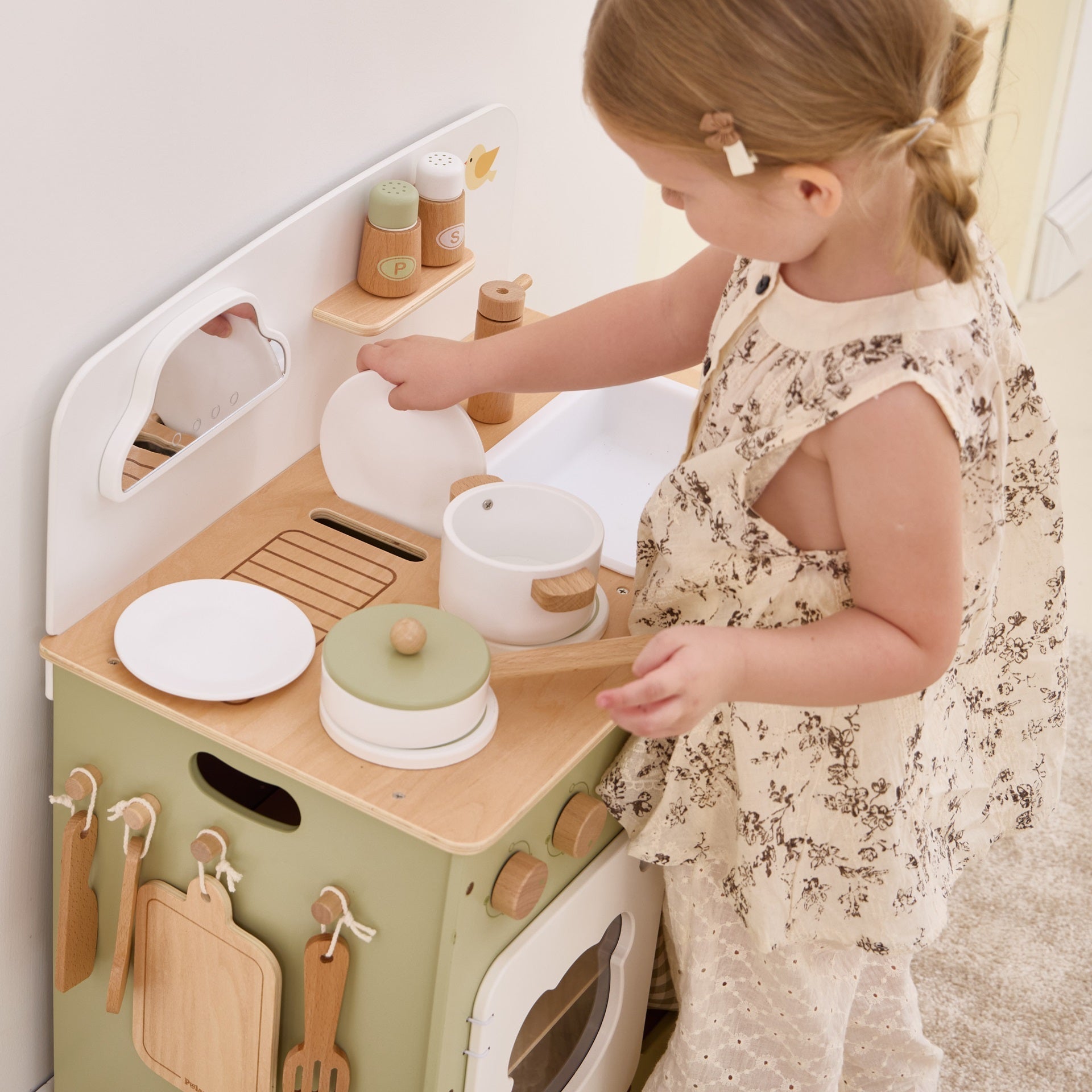 Child playing with a toy kitchen set in a bright room