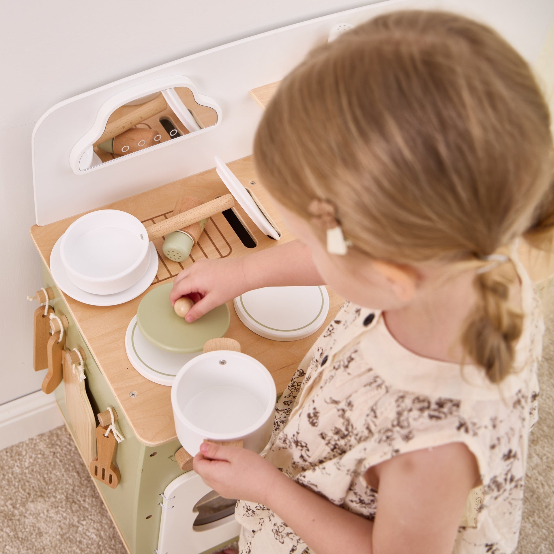 Child playing with a wooden toy kitchen set