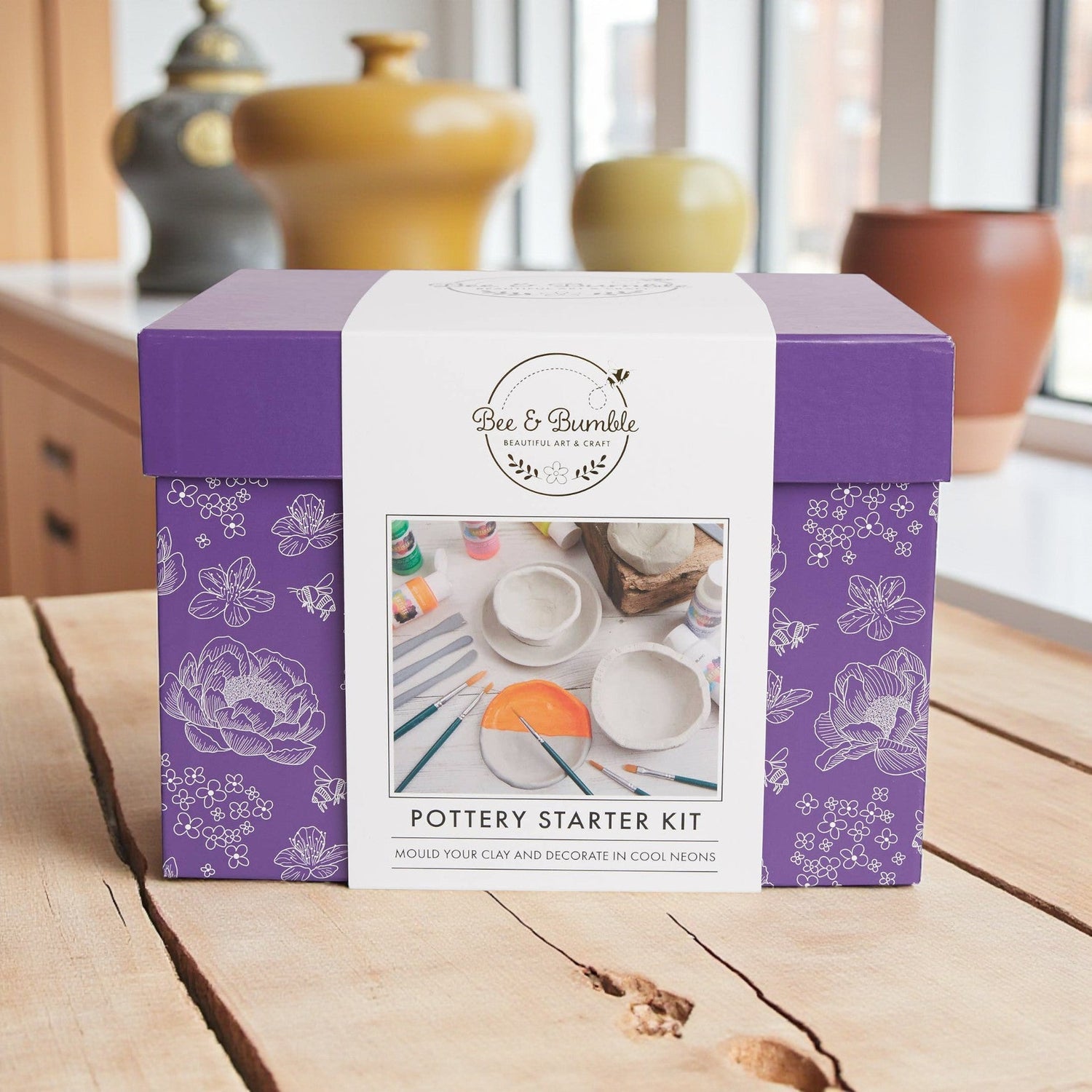 Purple pottery starter kit box with floral patterns on a wooden surface