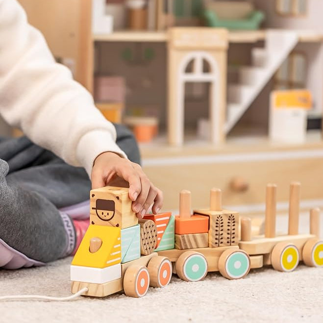 Child playing with a wooden toy train set on a carpeted floor.
