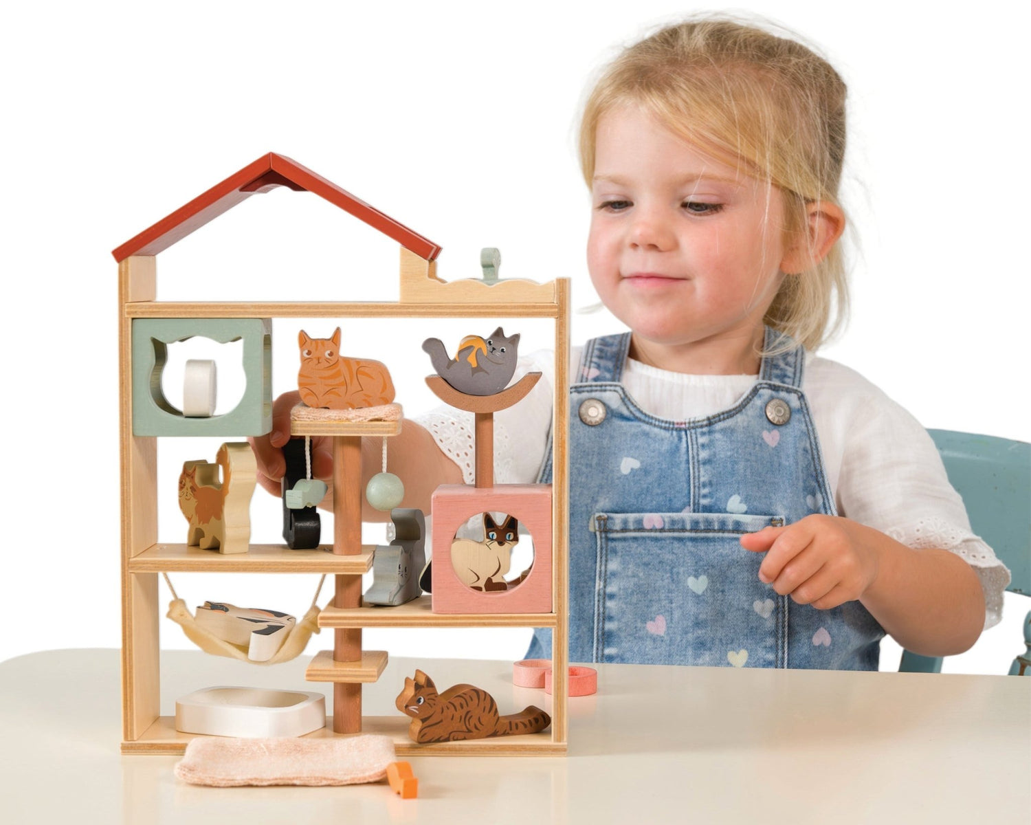 Child playing with a wooden toy house on a white background