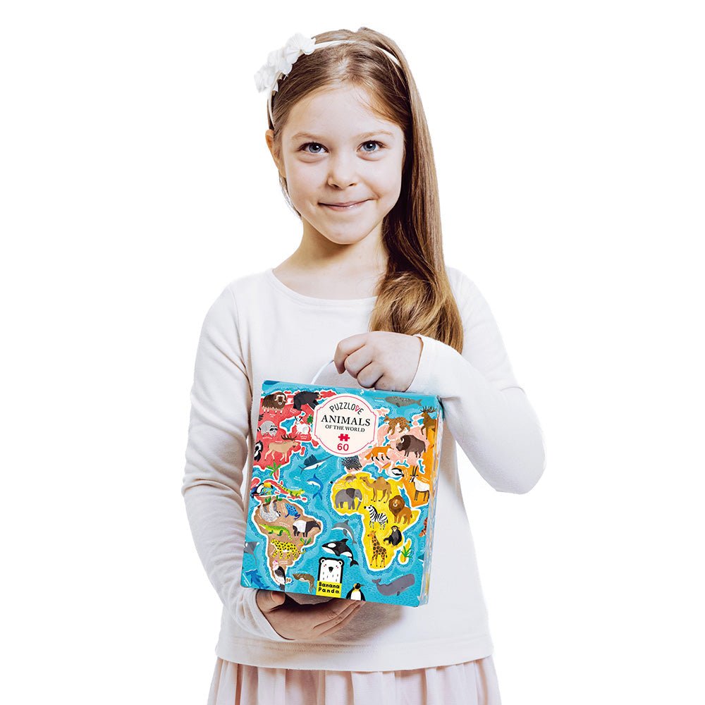 Young girl holding a colorful book titled 'Animals' against a white background