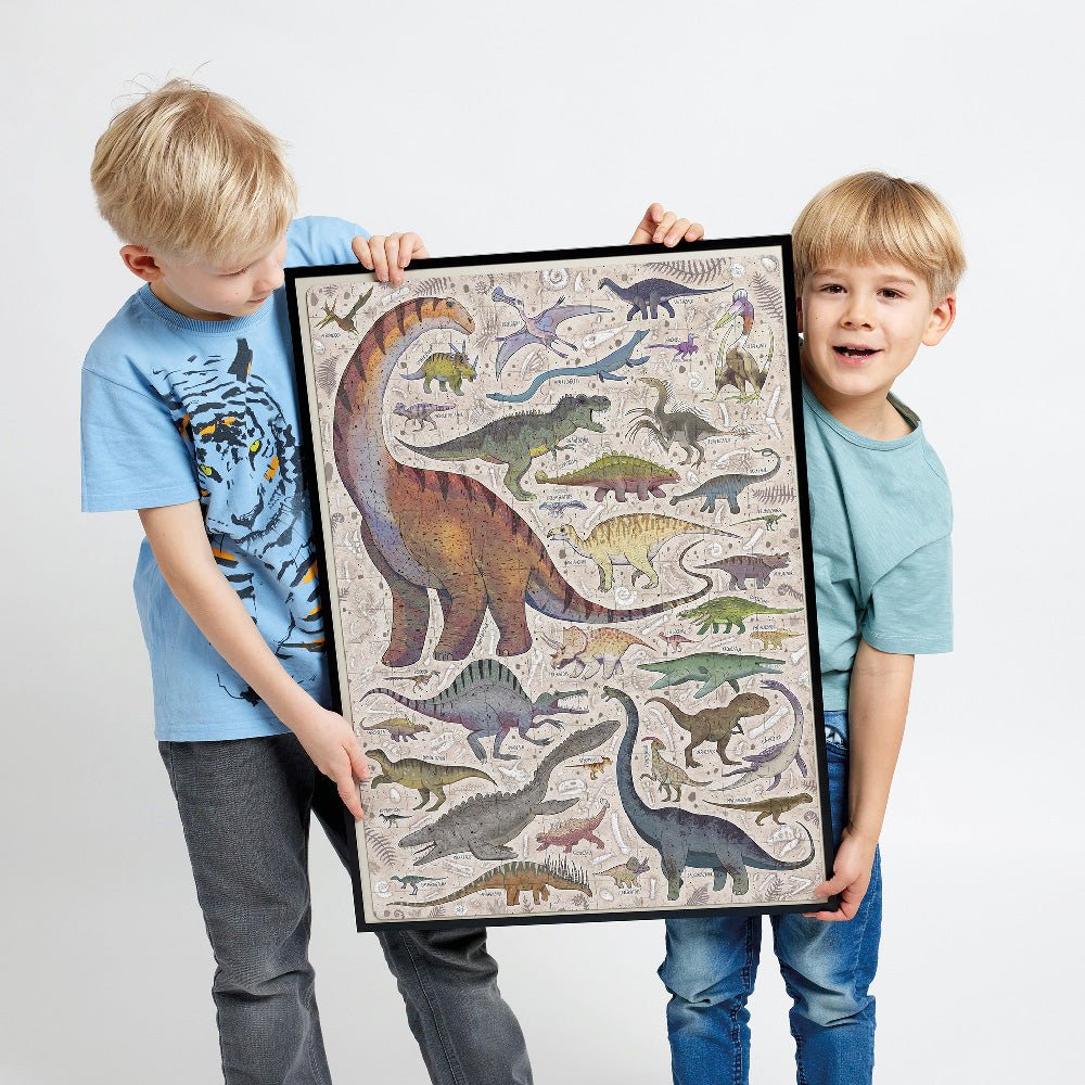 Two children holding a framed dinosaur mosaic art piece against a plain background