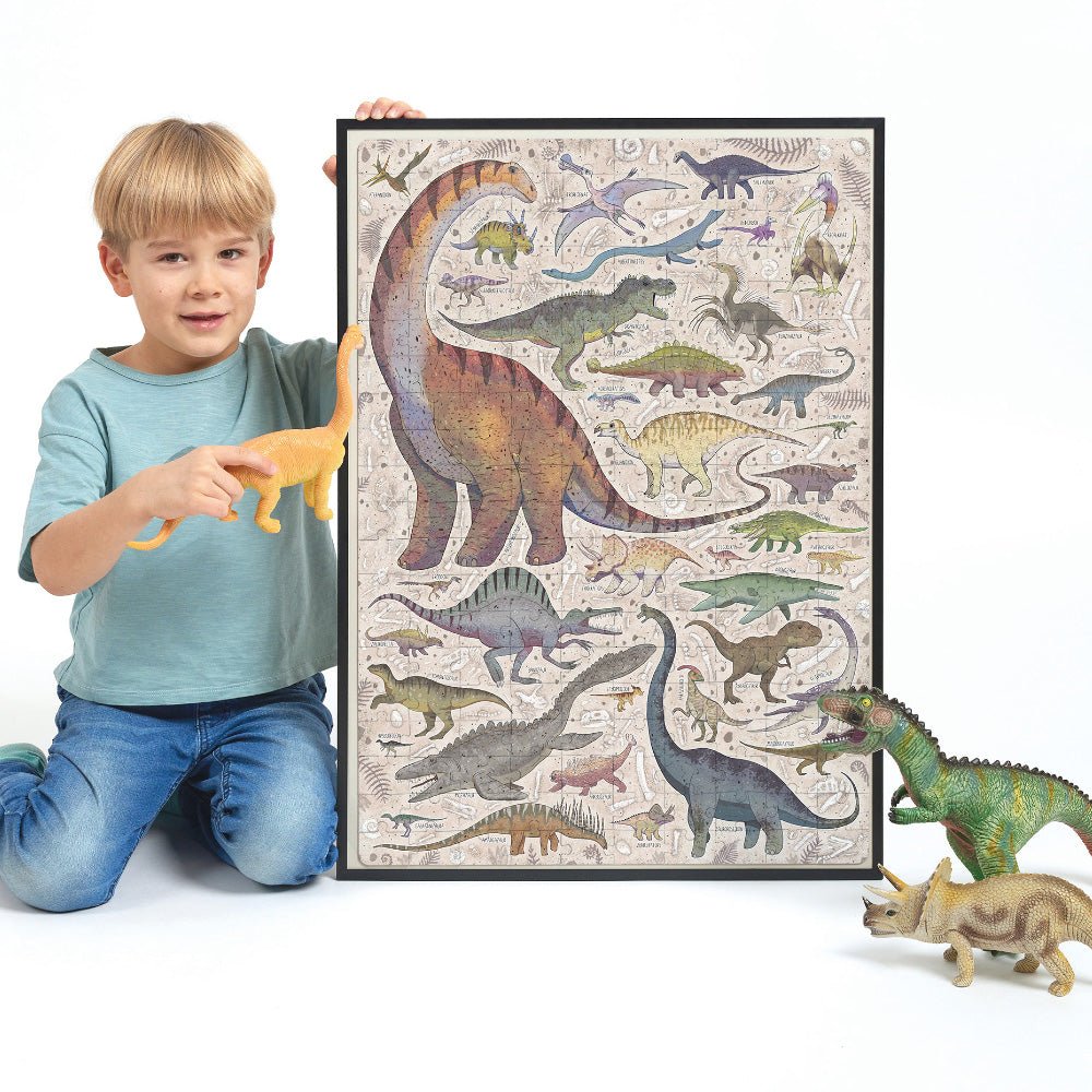 Child holding a framed dinosaur illustration with toy dinosaurs on a white background