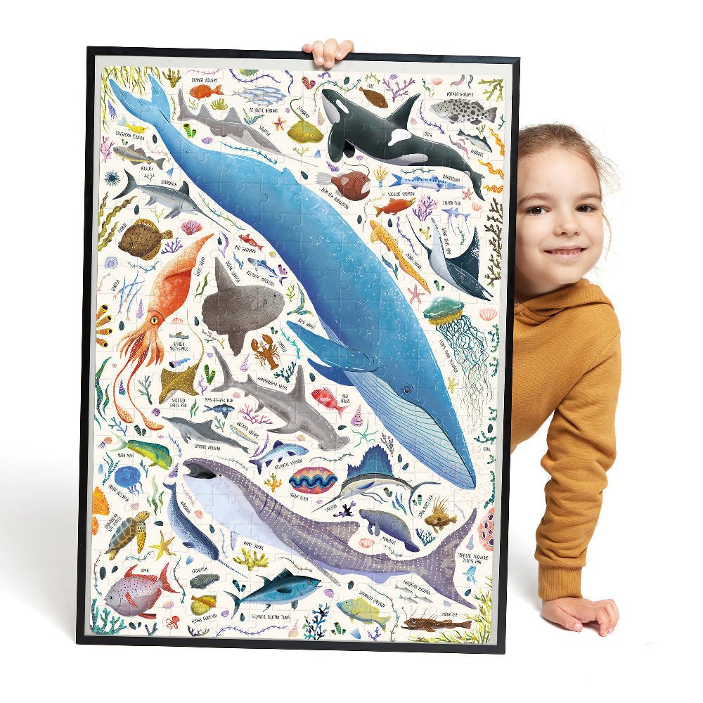 Child holding a large framed poster of marine animals on a white background