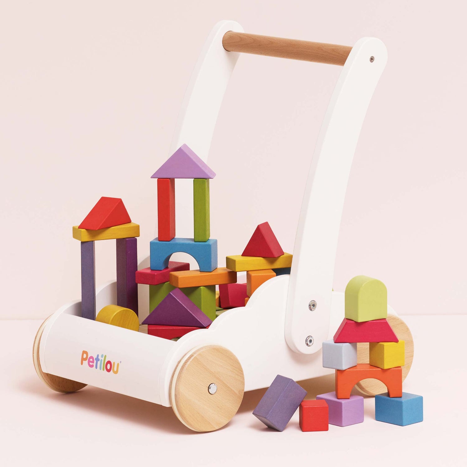 Colorful wooden blocks in a white cart with 'Petitou' branding on a light pink background